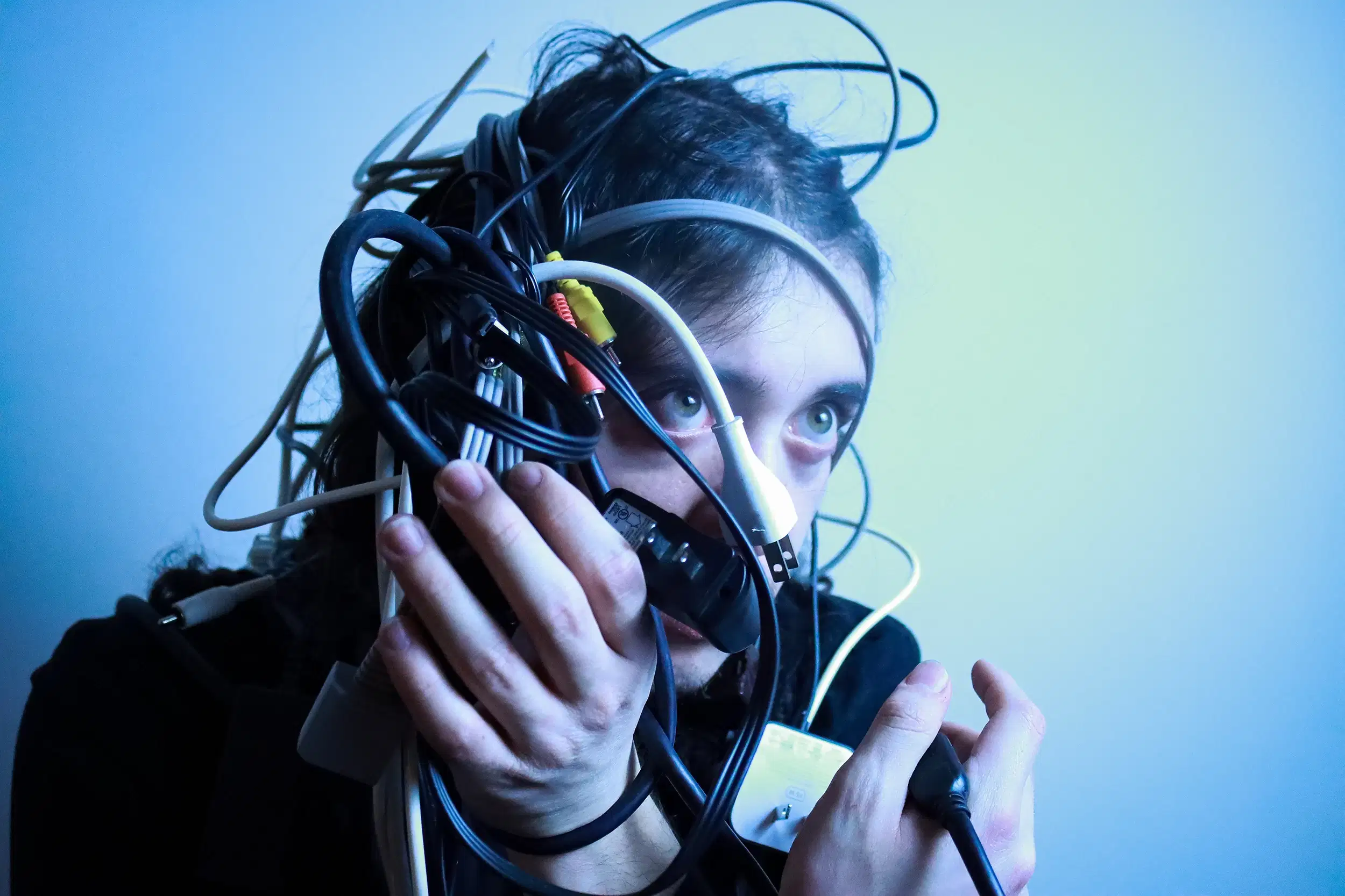 Self-portrait, a head covered in wires/cables, with cold, blue lighting.