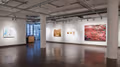 Exhibition photograph of “Between Picture and Viewer," showing paintings on two walls. On left is an abstract in pastels, on right are four photorealistic paintings in muted earth tones, and on far right is a large abstract painting in red and green.