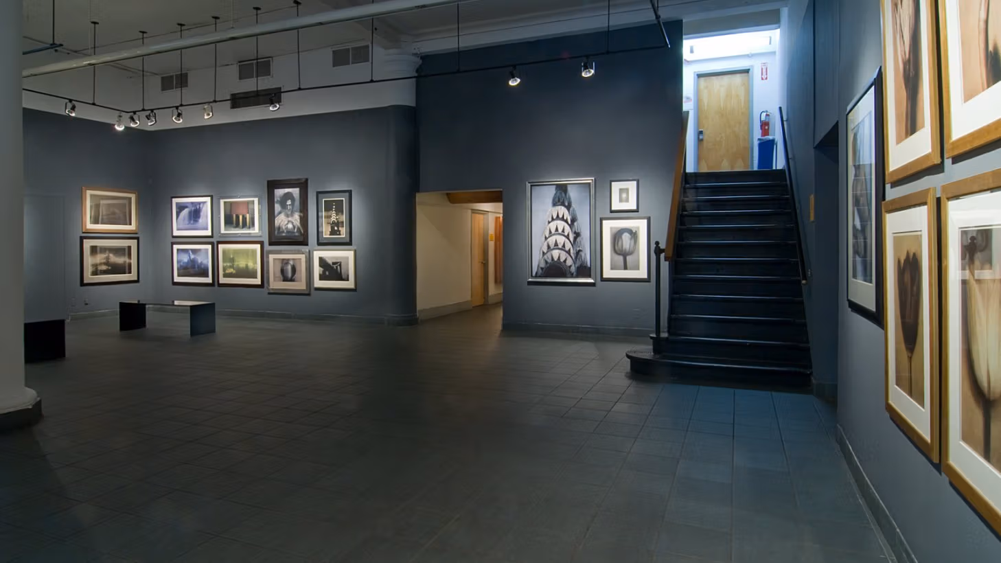 Photograph from inside lobby gallery of Visual Arts Museum, with framed photographs of buildings, flowers, celebrities, and family portraits by Sheila Metzner.