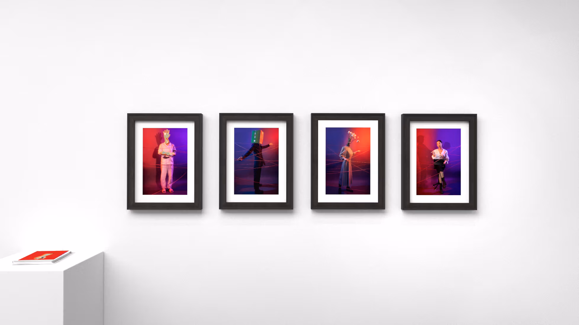 Four color photographs in black frames with a small red book on pedestal to their right.