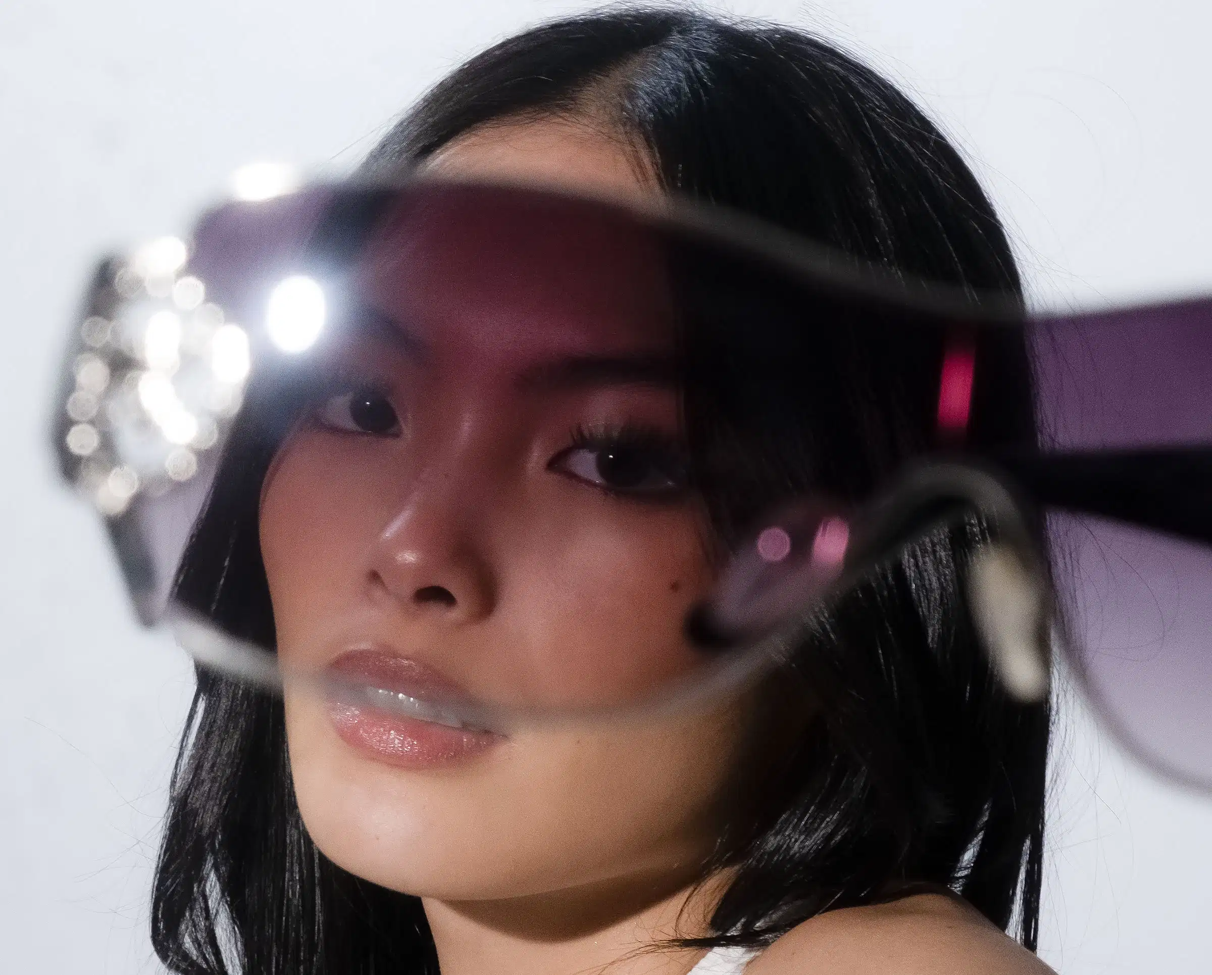 A woman's face peering through glasses 