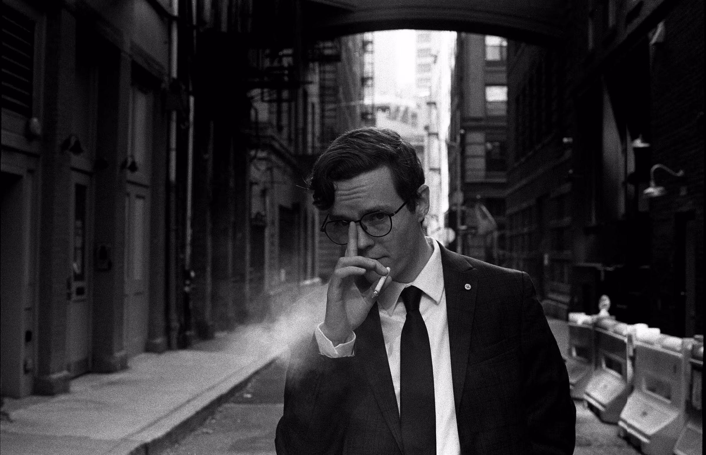 A man holding a cigarette in an alley