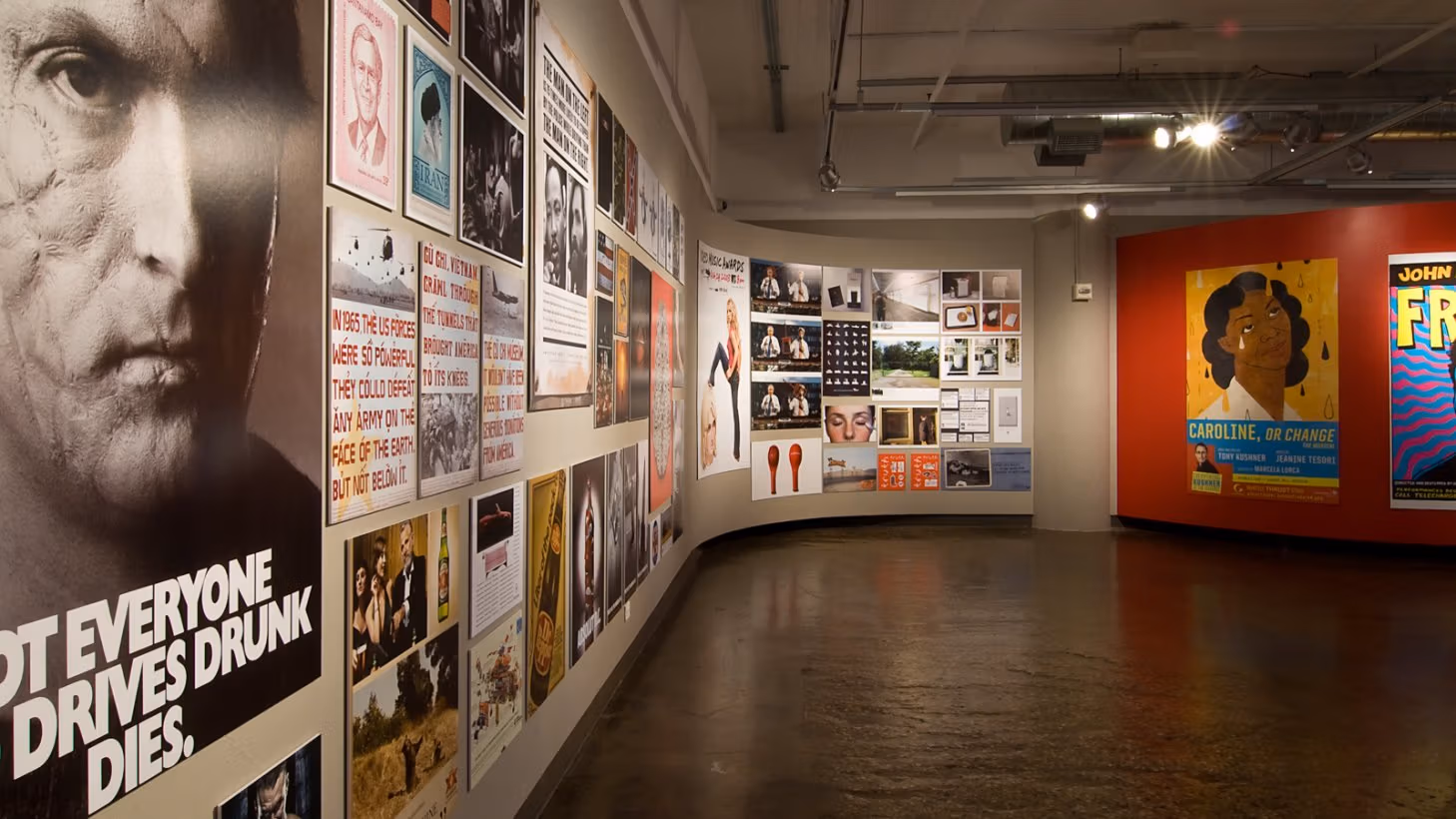 Photograph from inside SVA Chelsea Gallery with advertising graphics hung on walls.