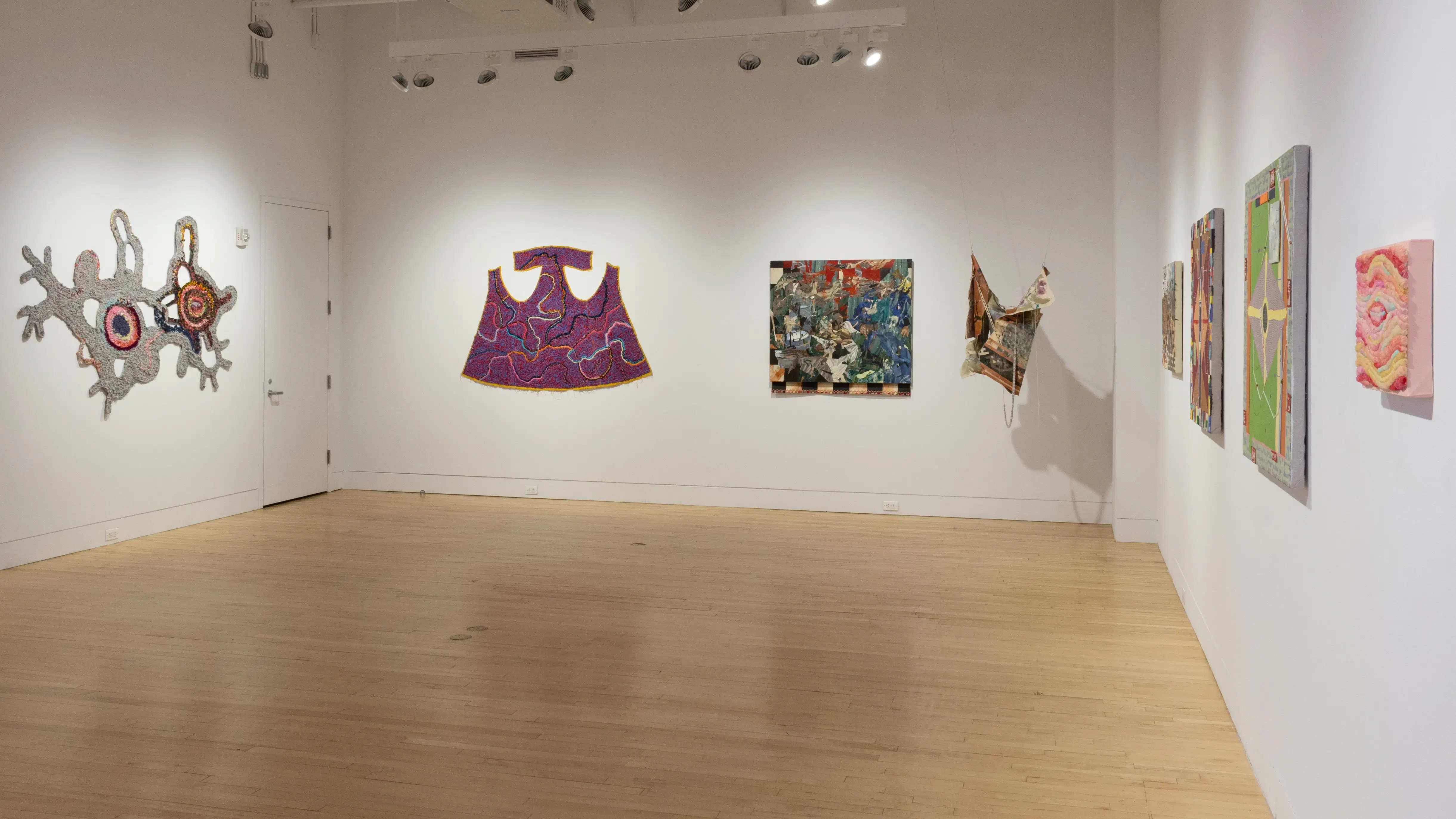 Installation image featuring three mixed media 2d works and four textile works.