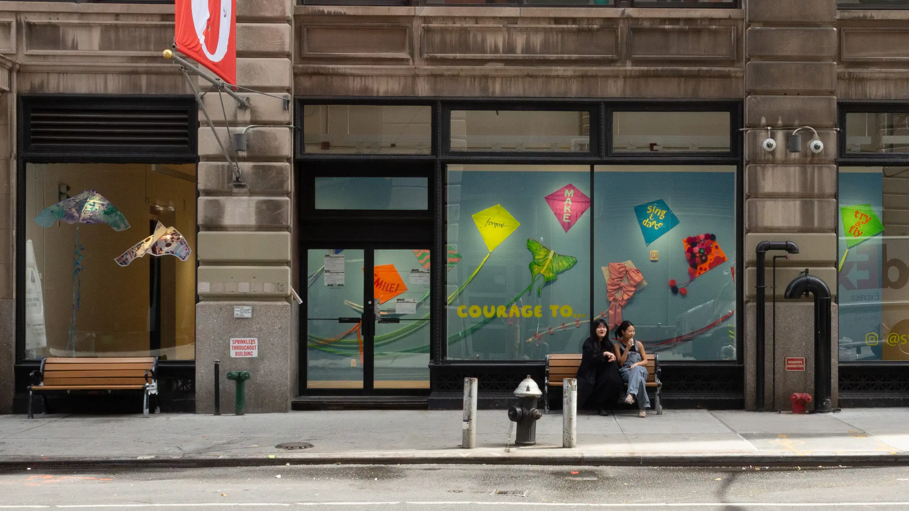 Through oversized windows, an installation of kites hangs on a wall and are suspended from the ceiling. 
