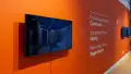 Installation image of an angled view of an orange wall with text and three monitors.