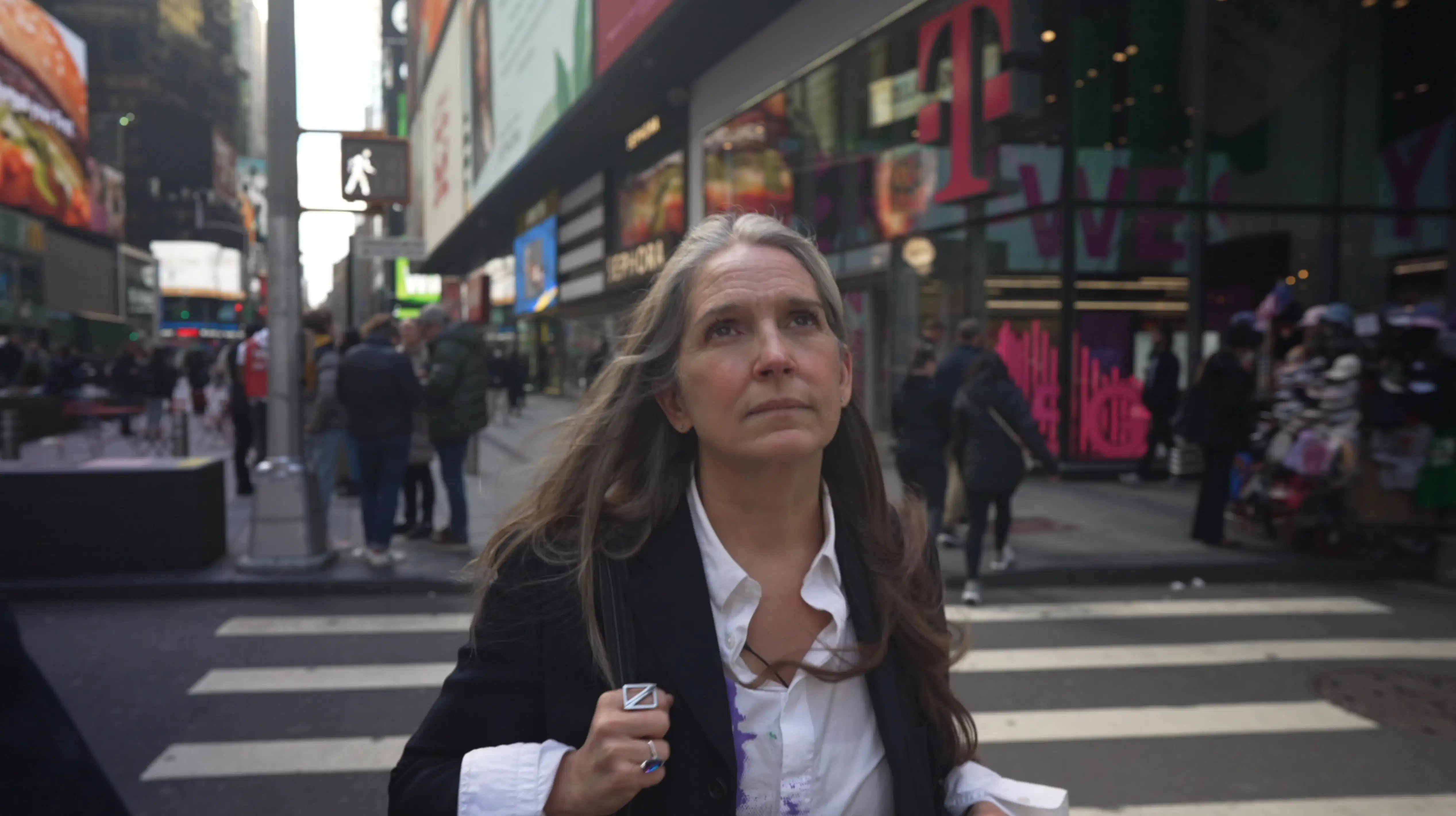 Woman walking in Times Square, looking up 
