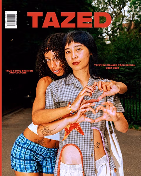 One person has her arms around another person. Both make a heart sign with their hands.