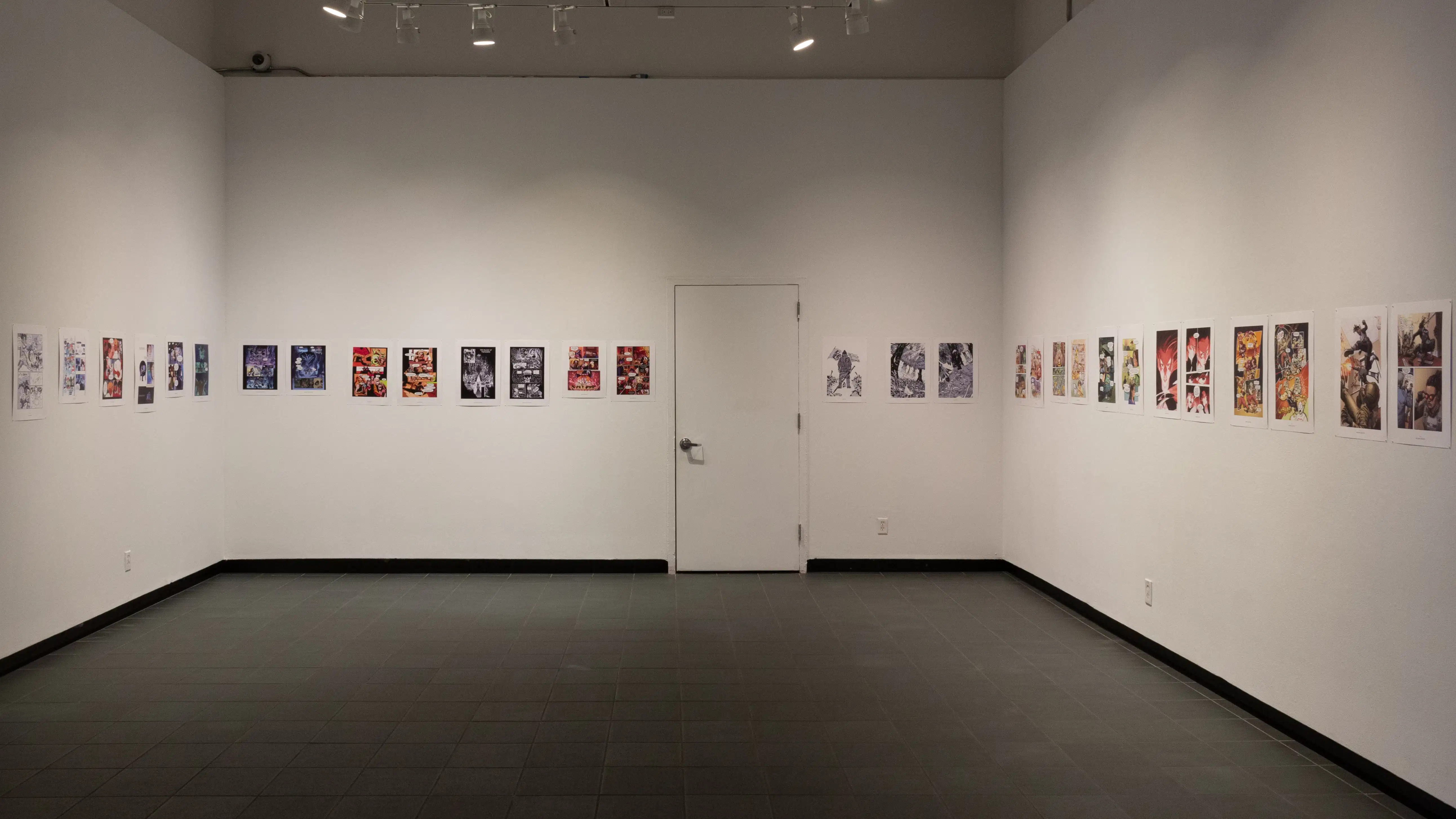 Install image showing an alcove with a door in the center back wall, and many prints lining the walls in a row.