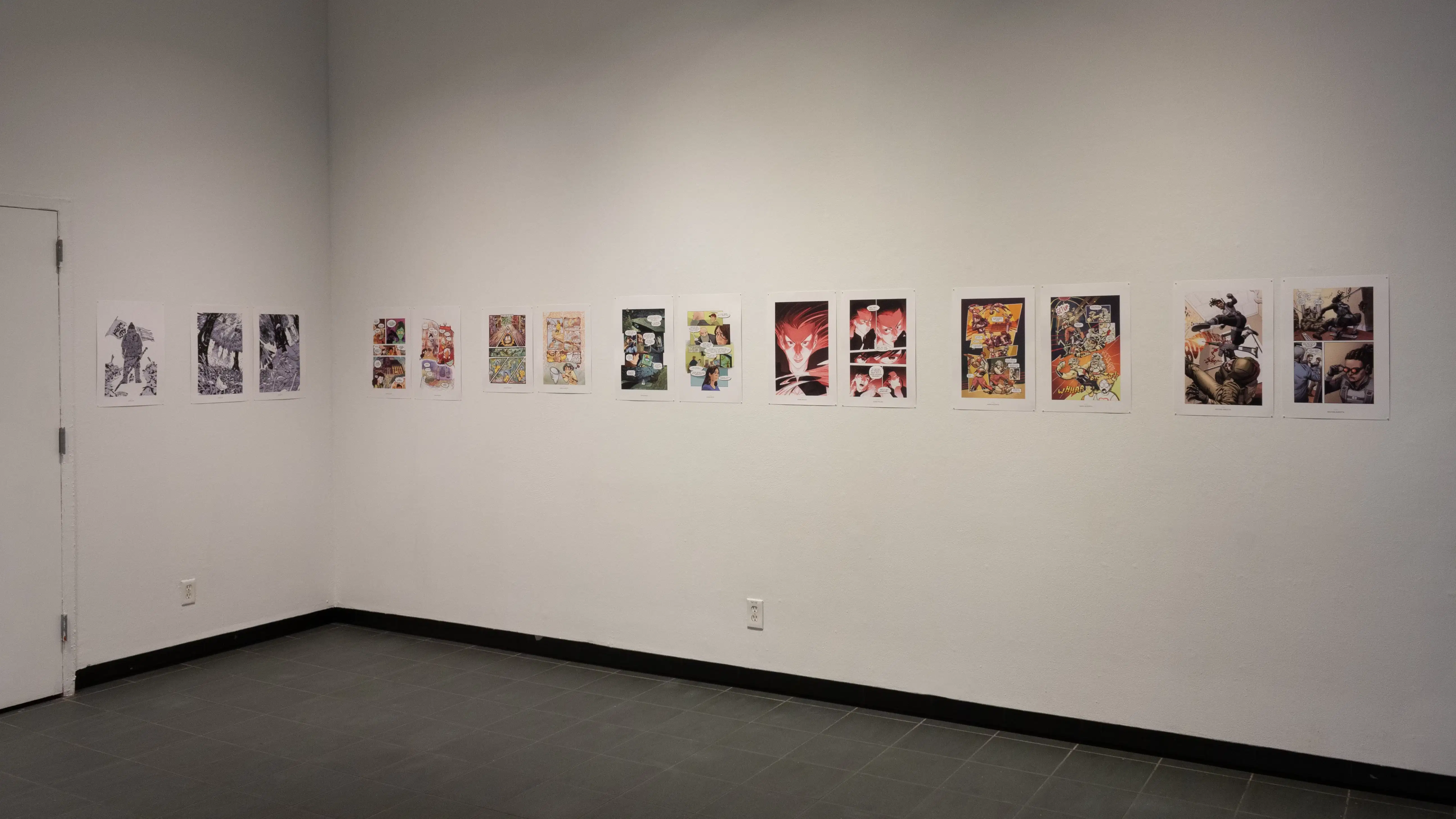 Install image showing an angled view of an alcove, with a doorway on the left and many prints lining the walls in a row.