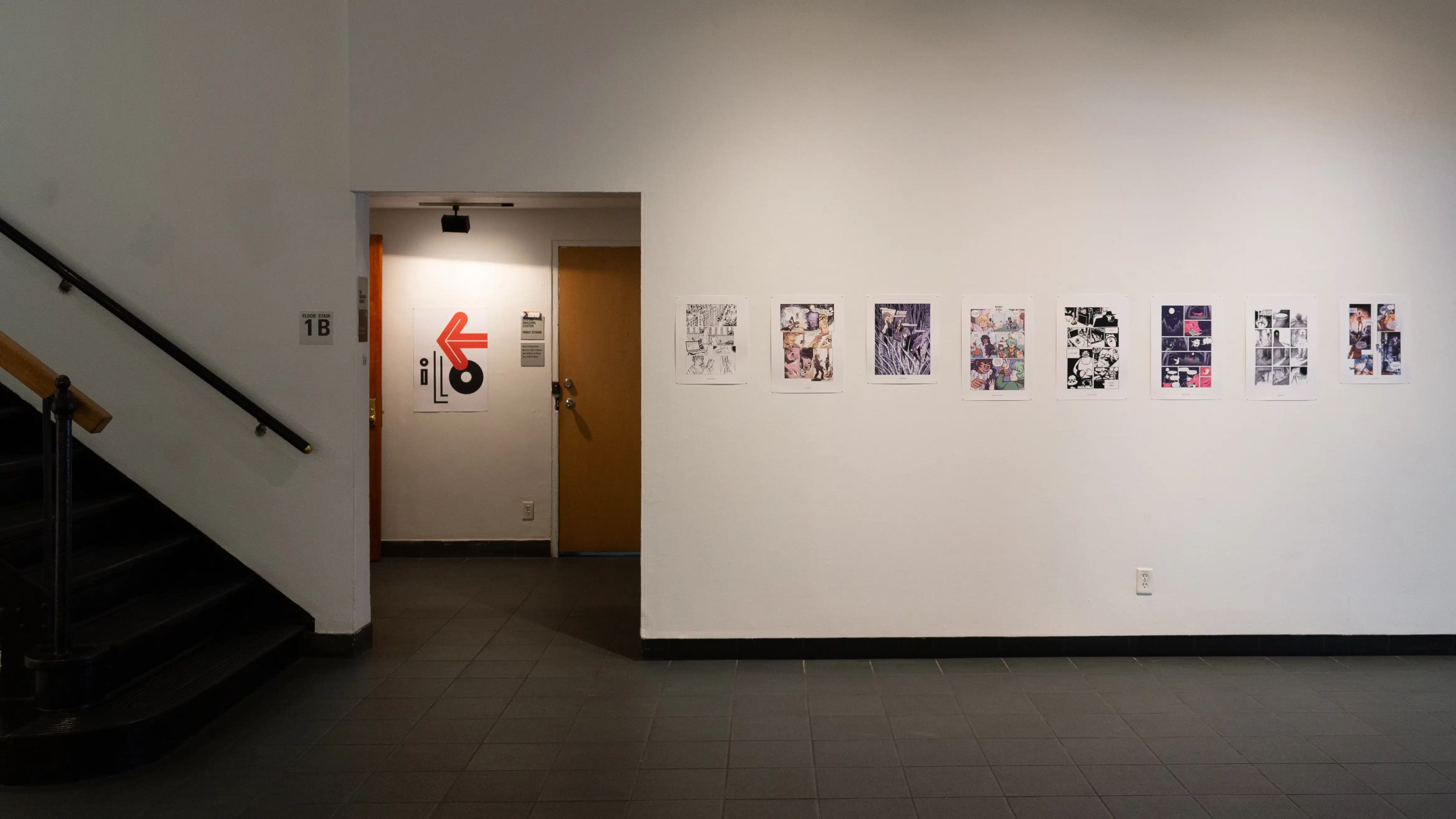 Install image showing a doorway leading to a foyer and many prints lining the walls in a row.