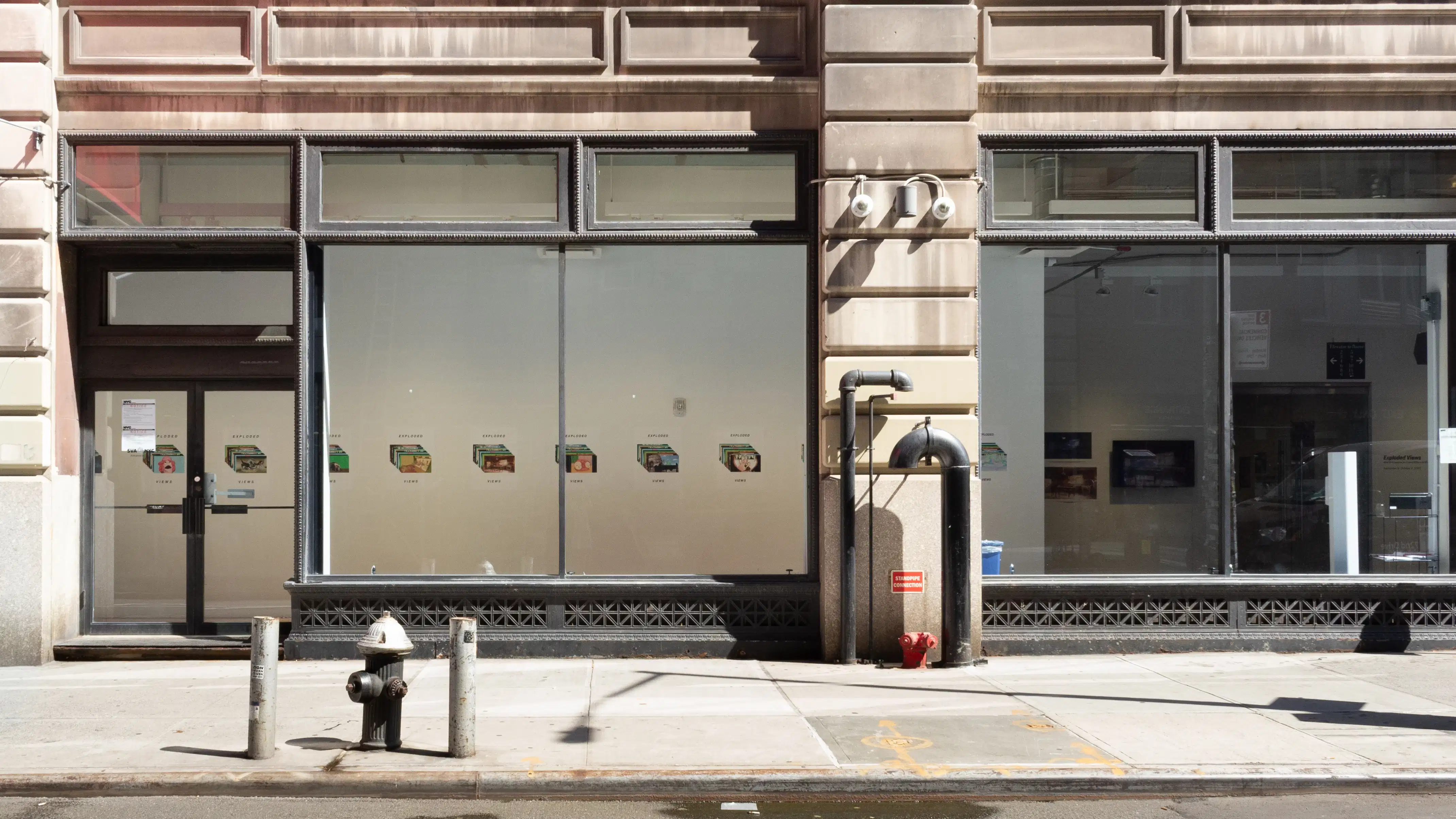 Installation image of street view featuring large windows with posters lining a hallway.