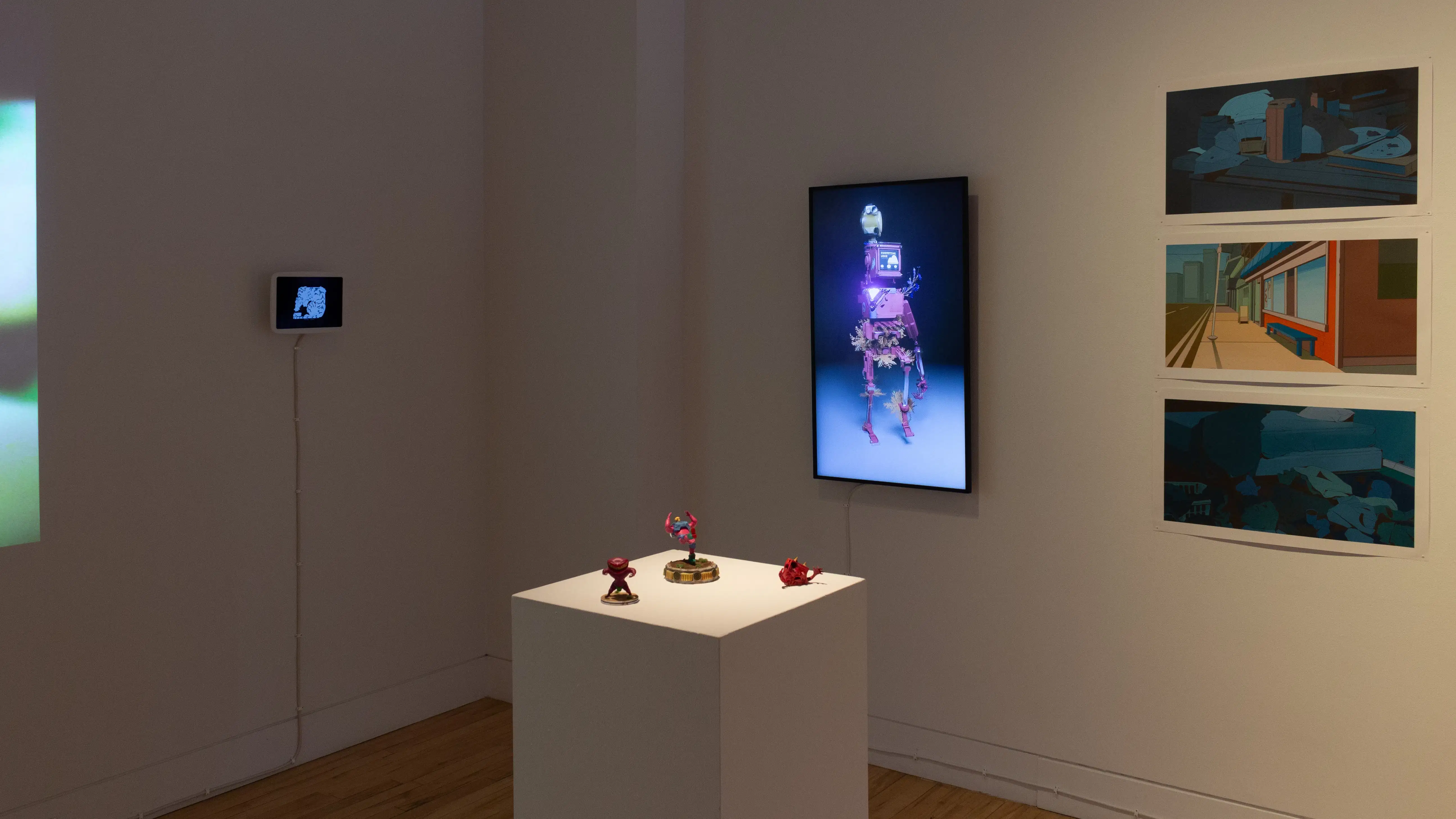 Installation image showing a pedestal with small figurines in the foreground, and two monitors and 3 prints on the walls in the background.