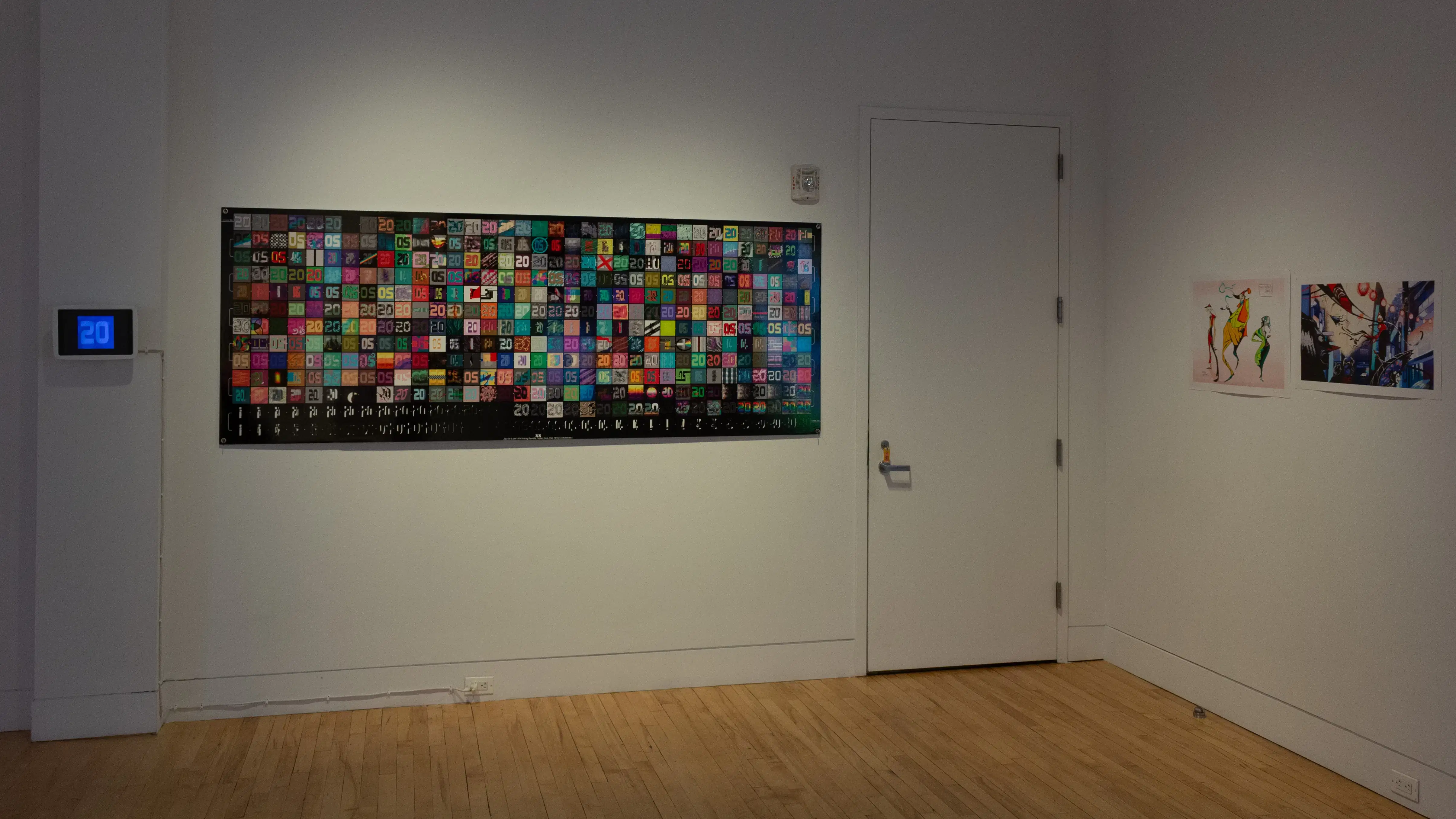 Installation image showing a large print of gridded colors, a small monitor, and two smaller prints.