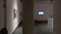 Another view of the SVA Gramercy Gallery. Framed photographs, video monitors, and objects on pedestals are all visible.