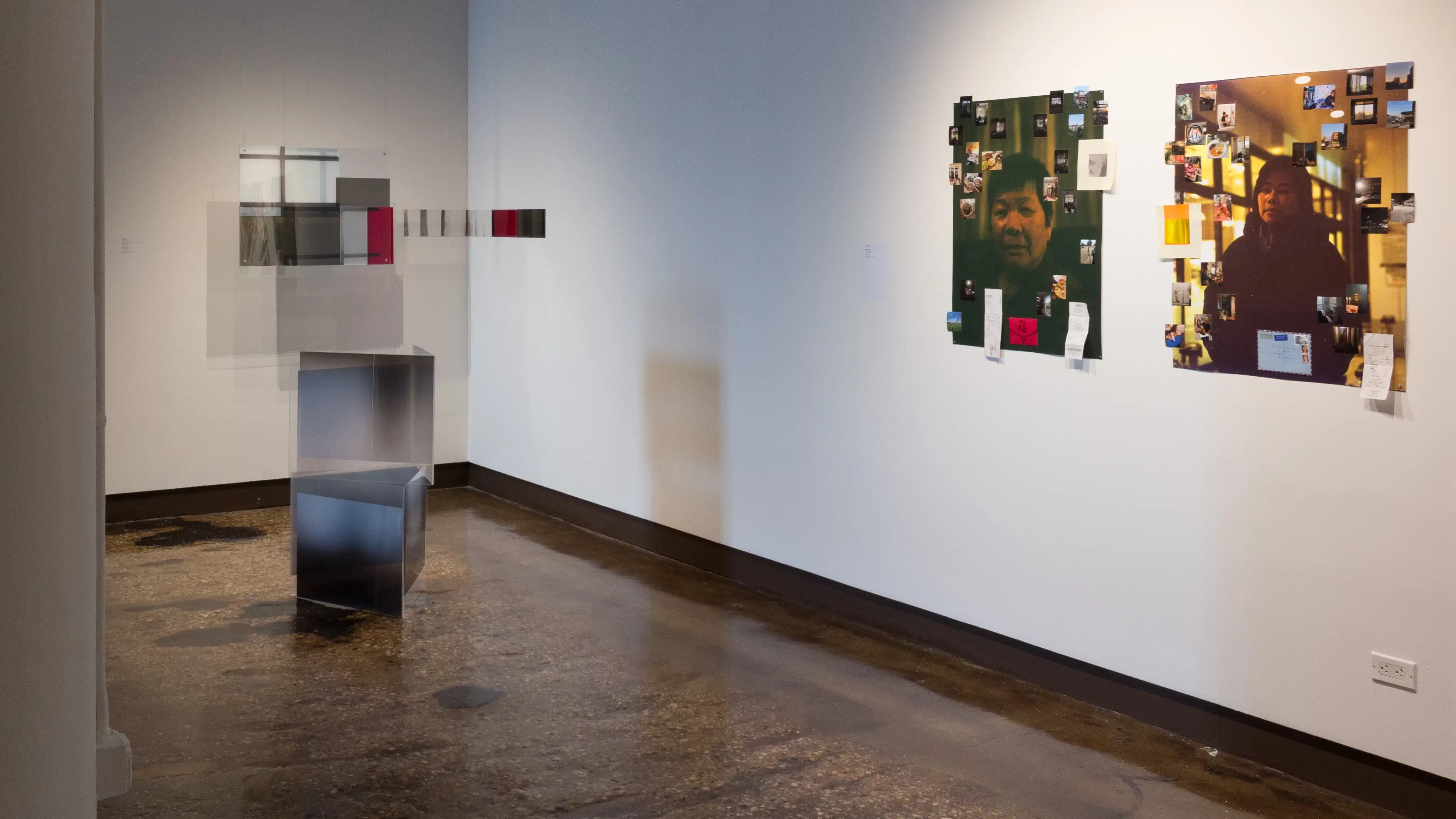 In one corner, an installation of photos and plexi-glass are suspended in air and stacked on the ground. On the adjacent wall, two large photos of an older man and woman are collaged with smaller photos and paper ephemera.