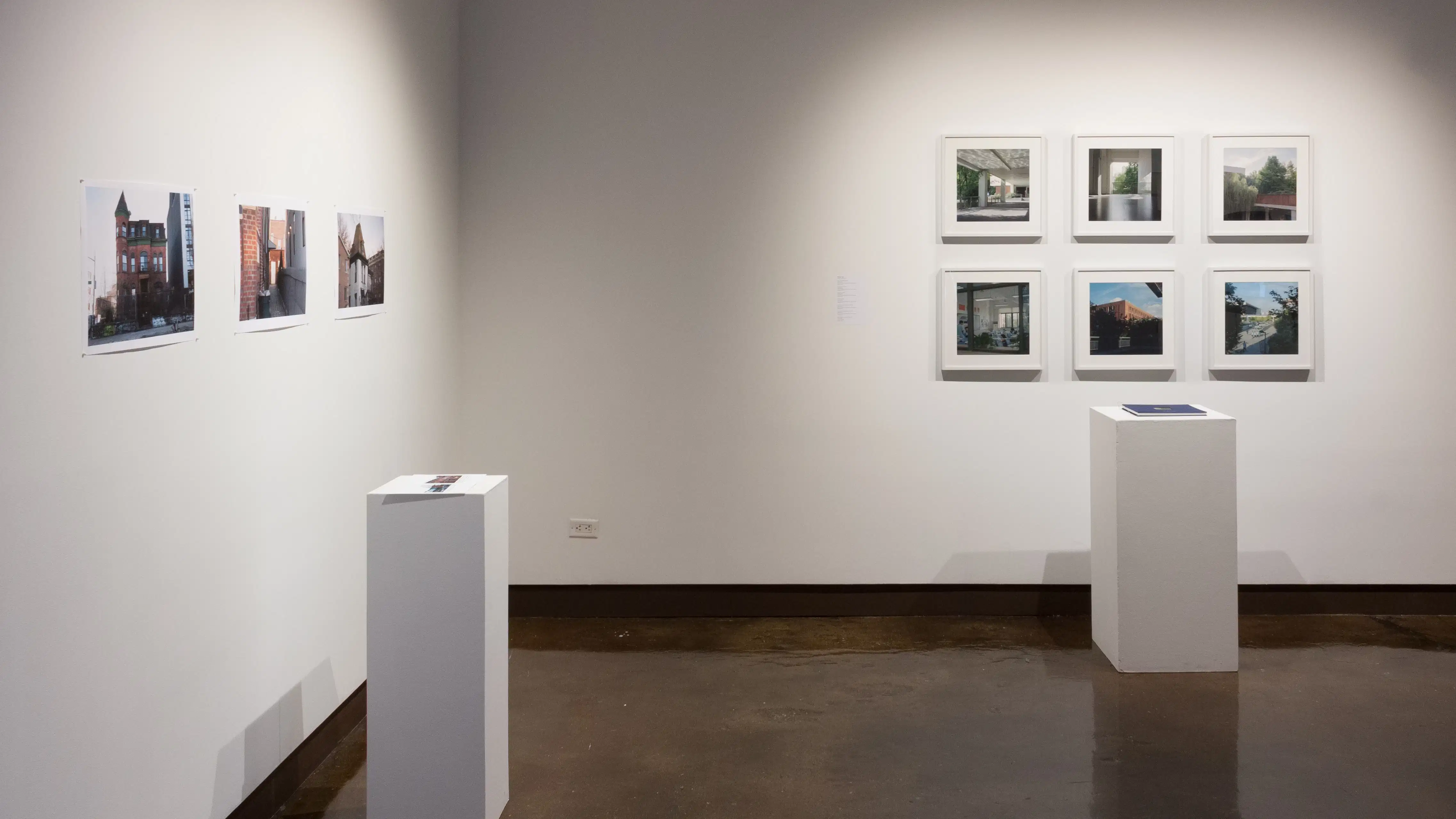 In one corner of gallery four there are two pedestals with rows of color photographs behind them. The photos are of houses and other architecture.