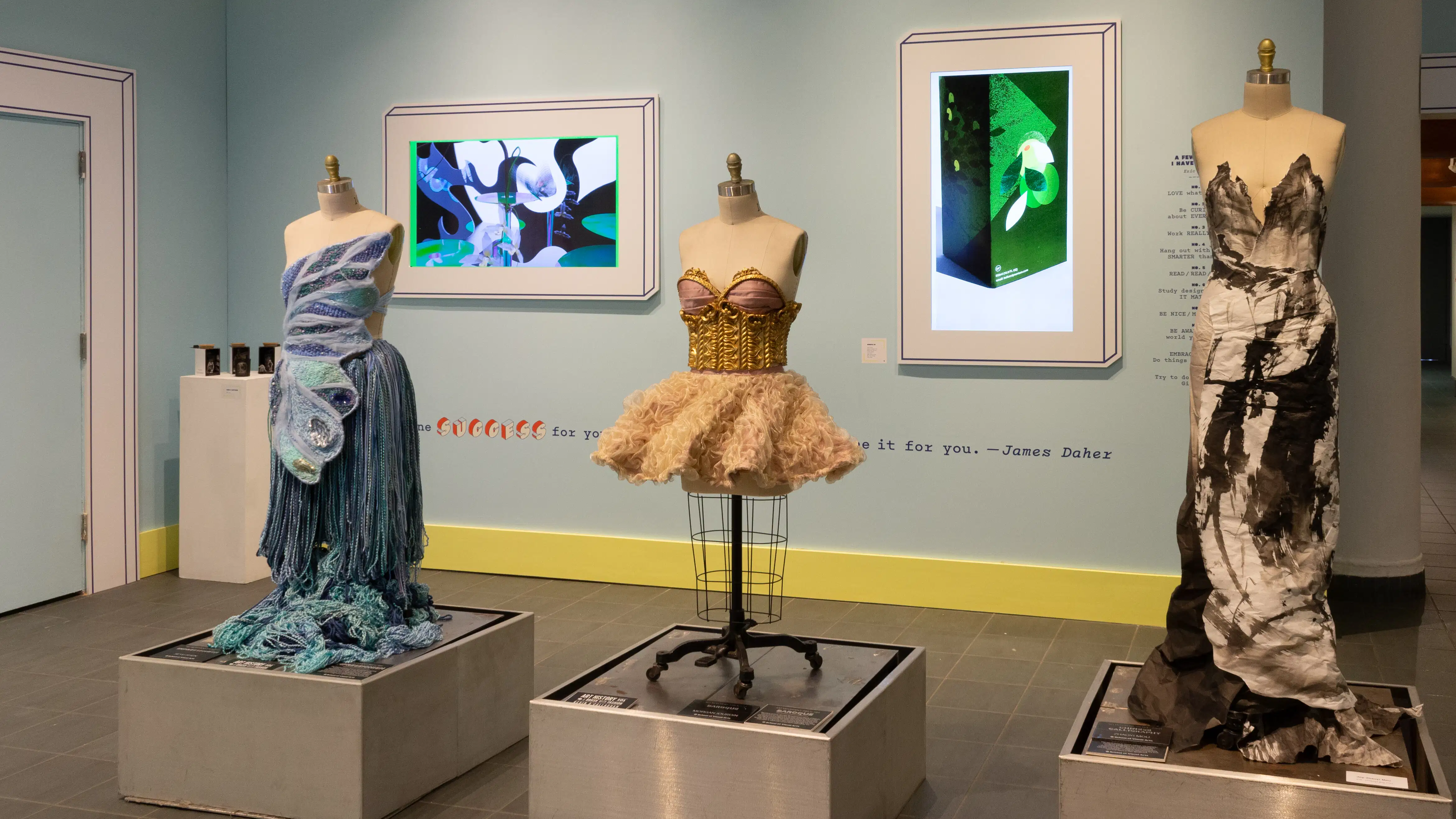 A third angled view of alcove in the lobby. Three mannequins in dresses can be seen, and two monitors displaying branding graphics.