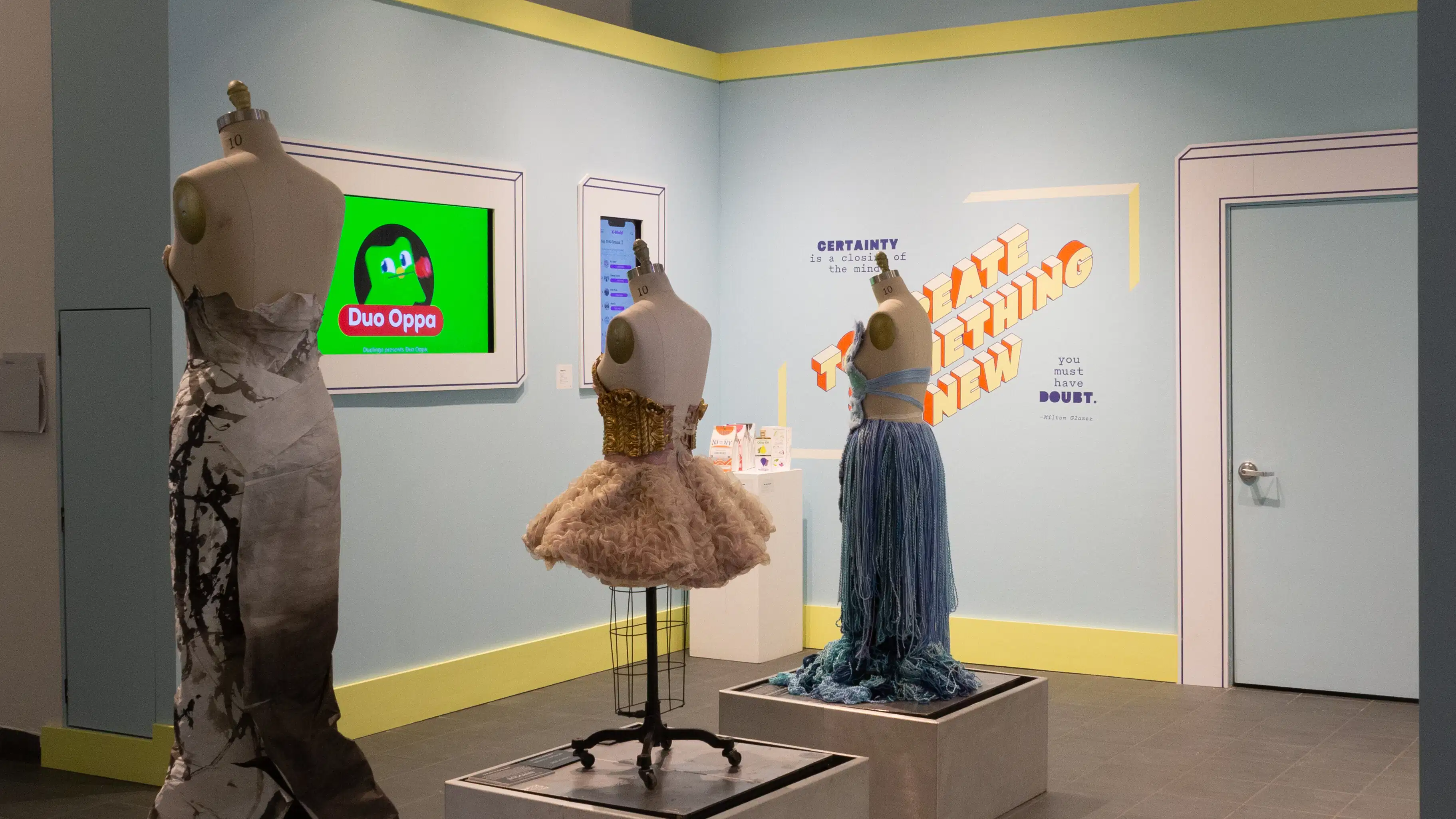  A second angled view of alcove in the lobby. Three mannequins in dresses can be seen, and two monitors displaying branding graphics.
