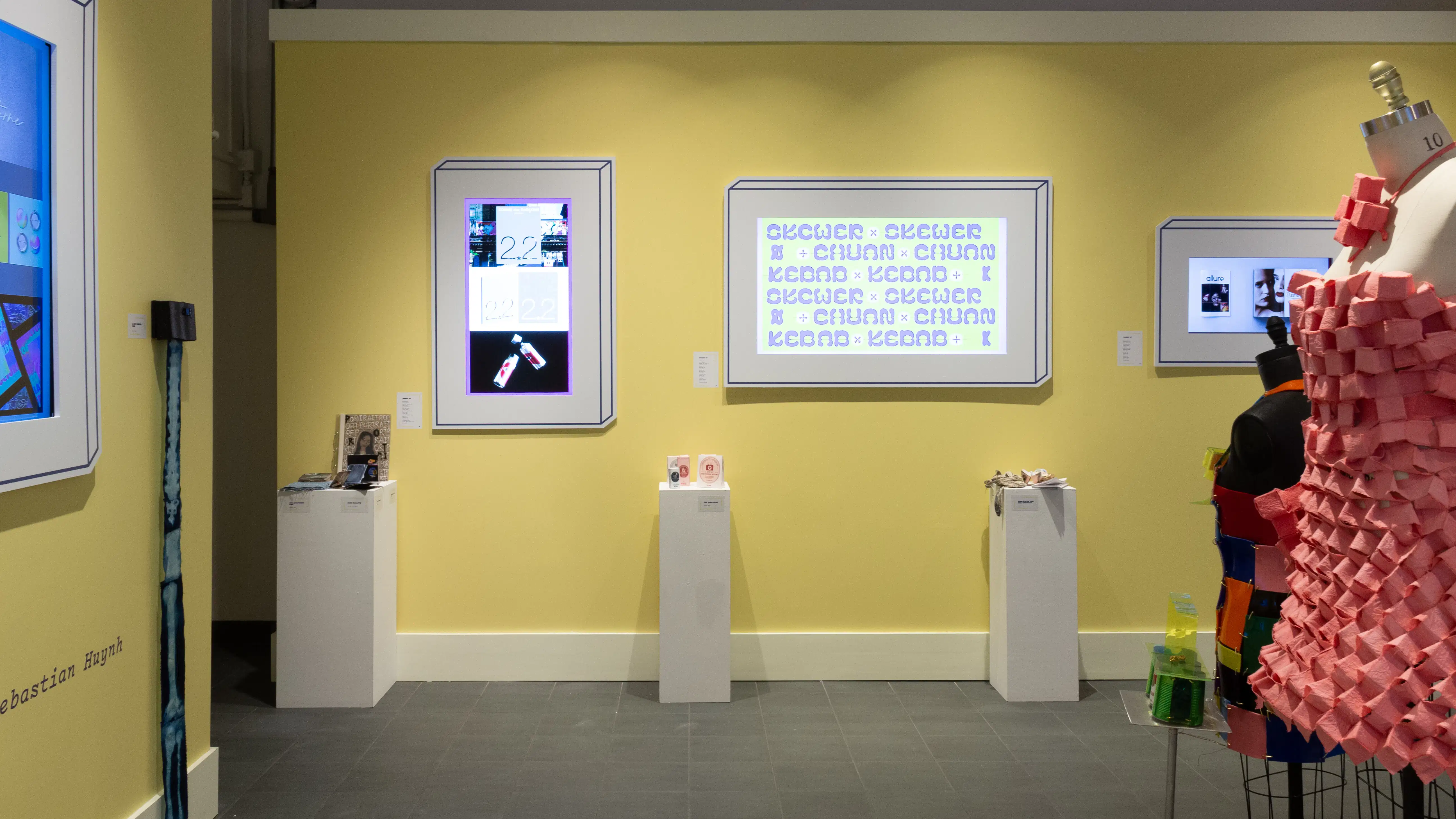 View of the wall to the left when you walk in gallery two. Three pedestals with small objects and three monitors can be seen along the wall.