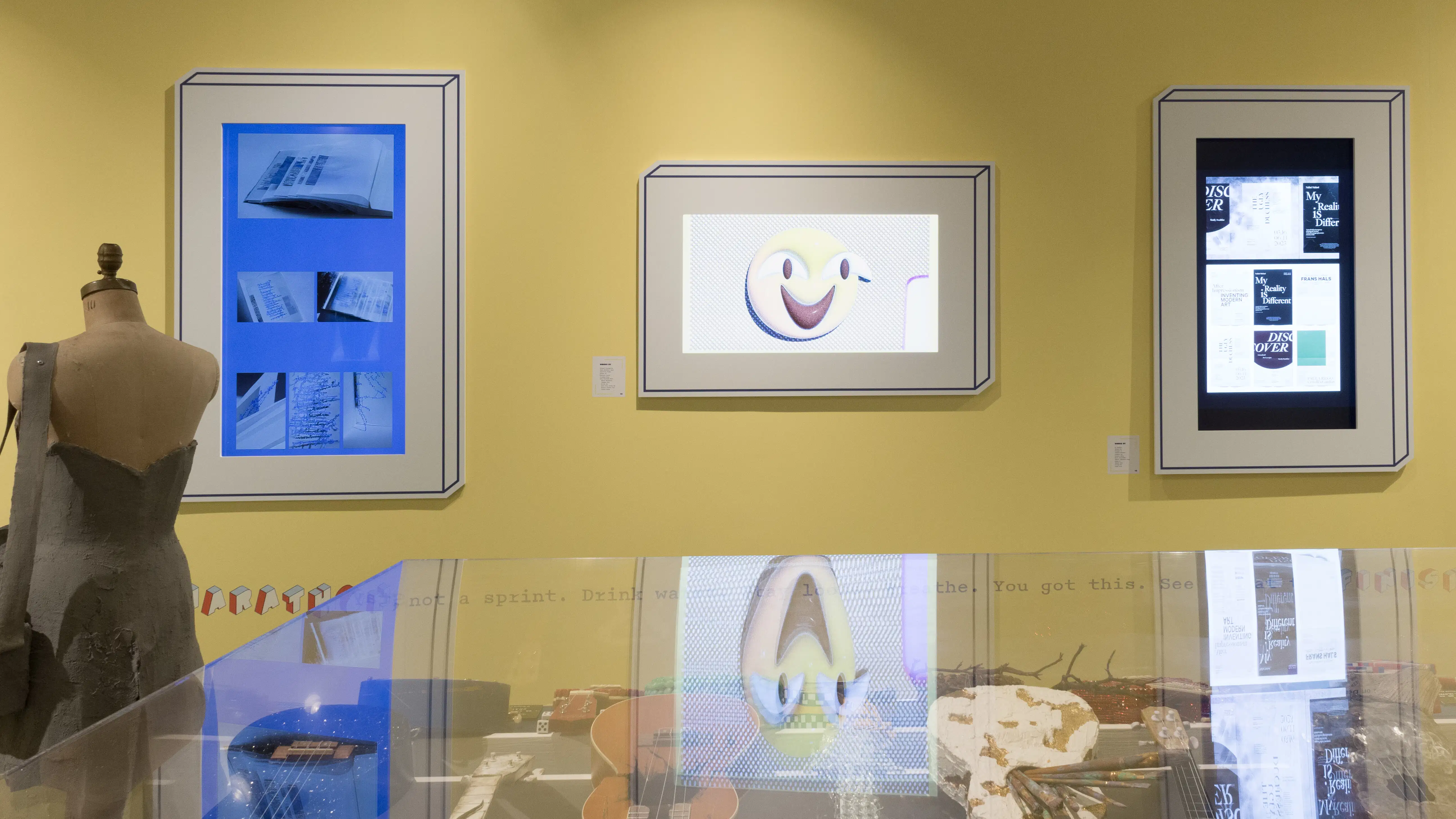 View over the plexi vitrine of three monitors in the background along the wall.