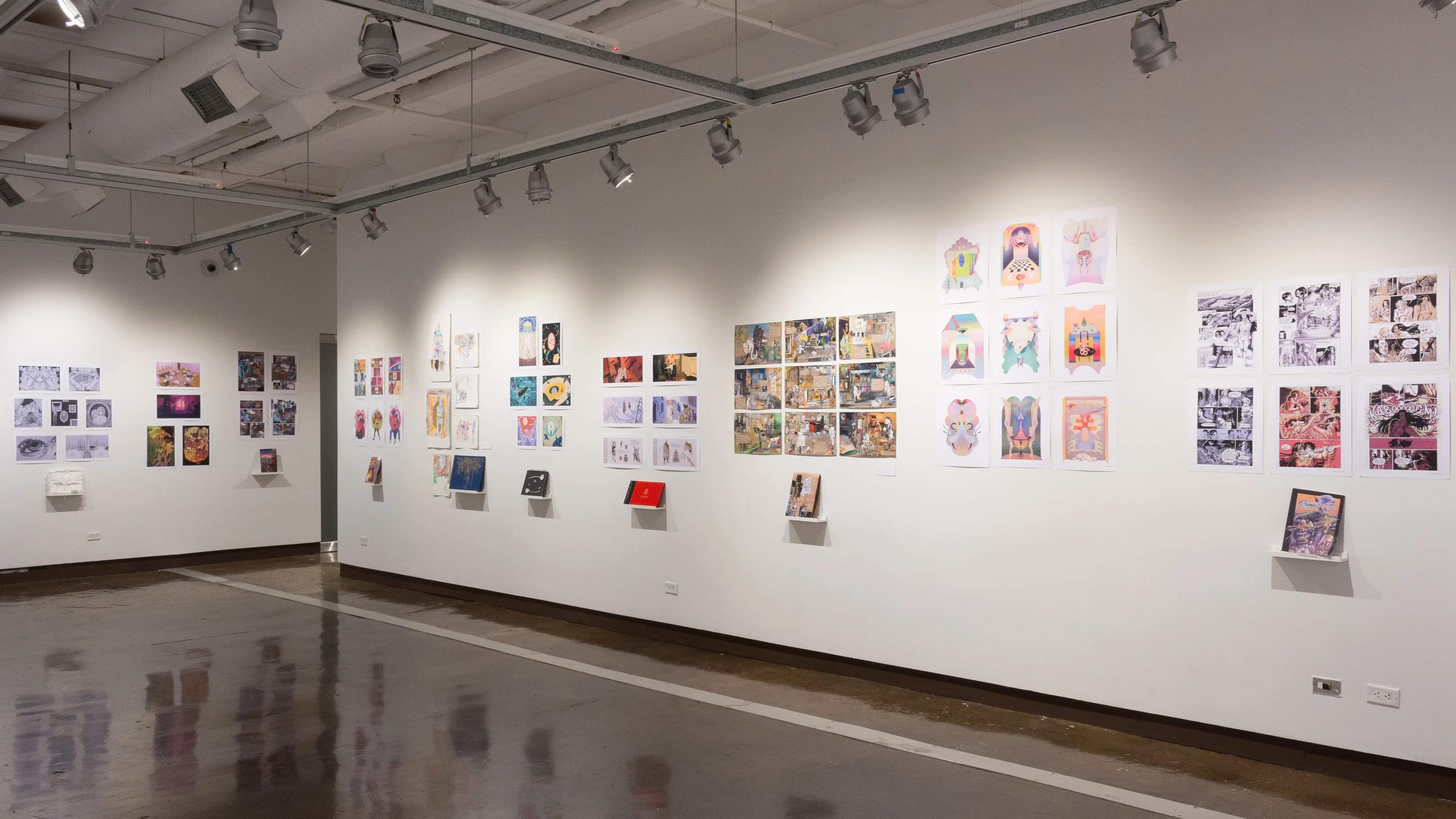 In the second gallery space, many student projects with books, prints, and original works are on view. They differ in style, color, and dimensions.