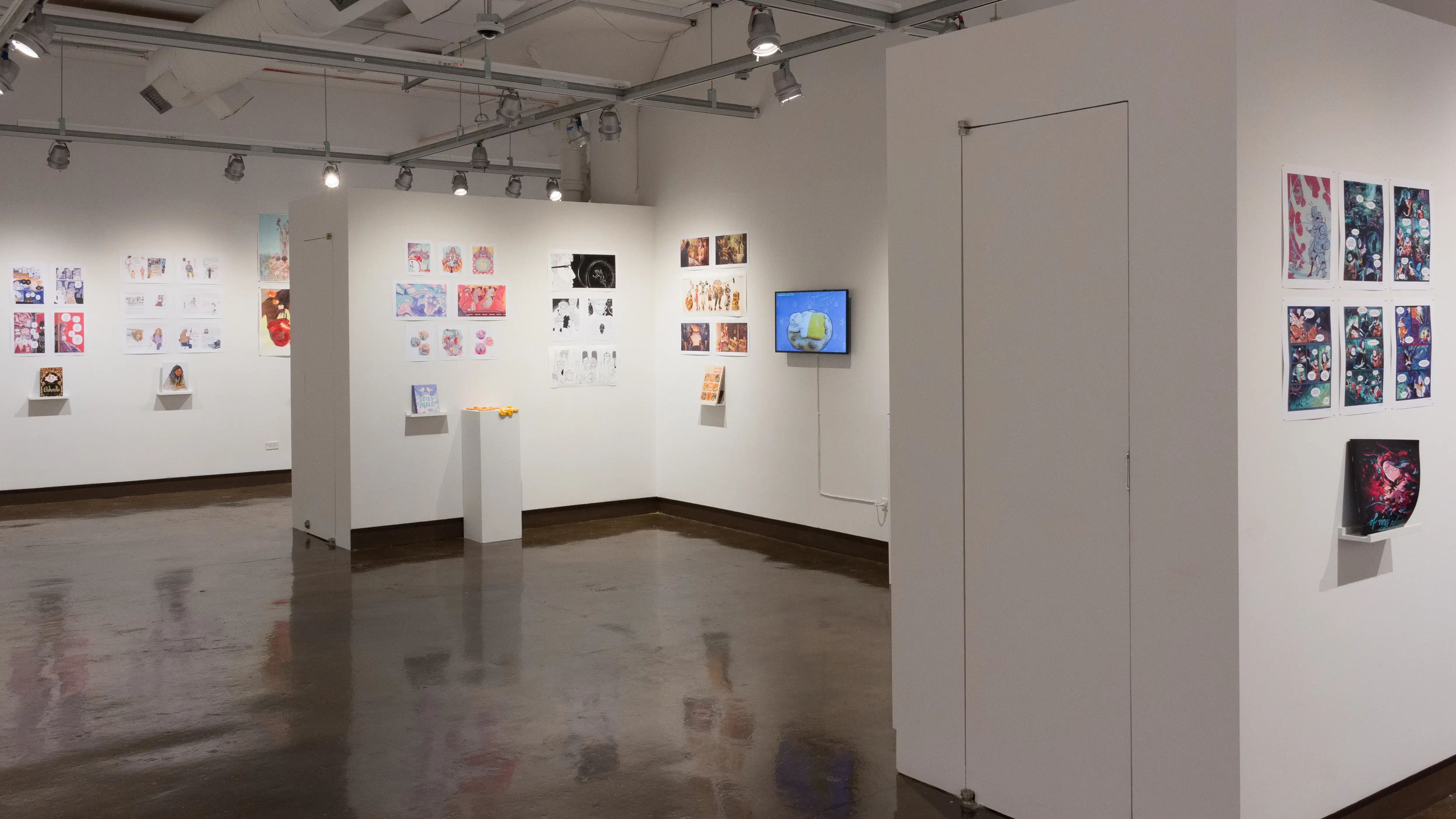 The third gallery space is visible from another angle. More student work can be seen on surrounding walls.