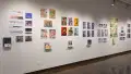 Prints, originals, and books are all displayed on a wall of gallery three.