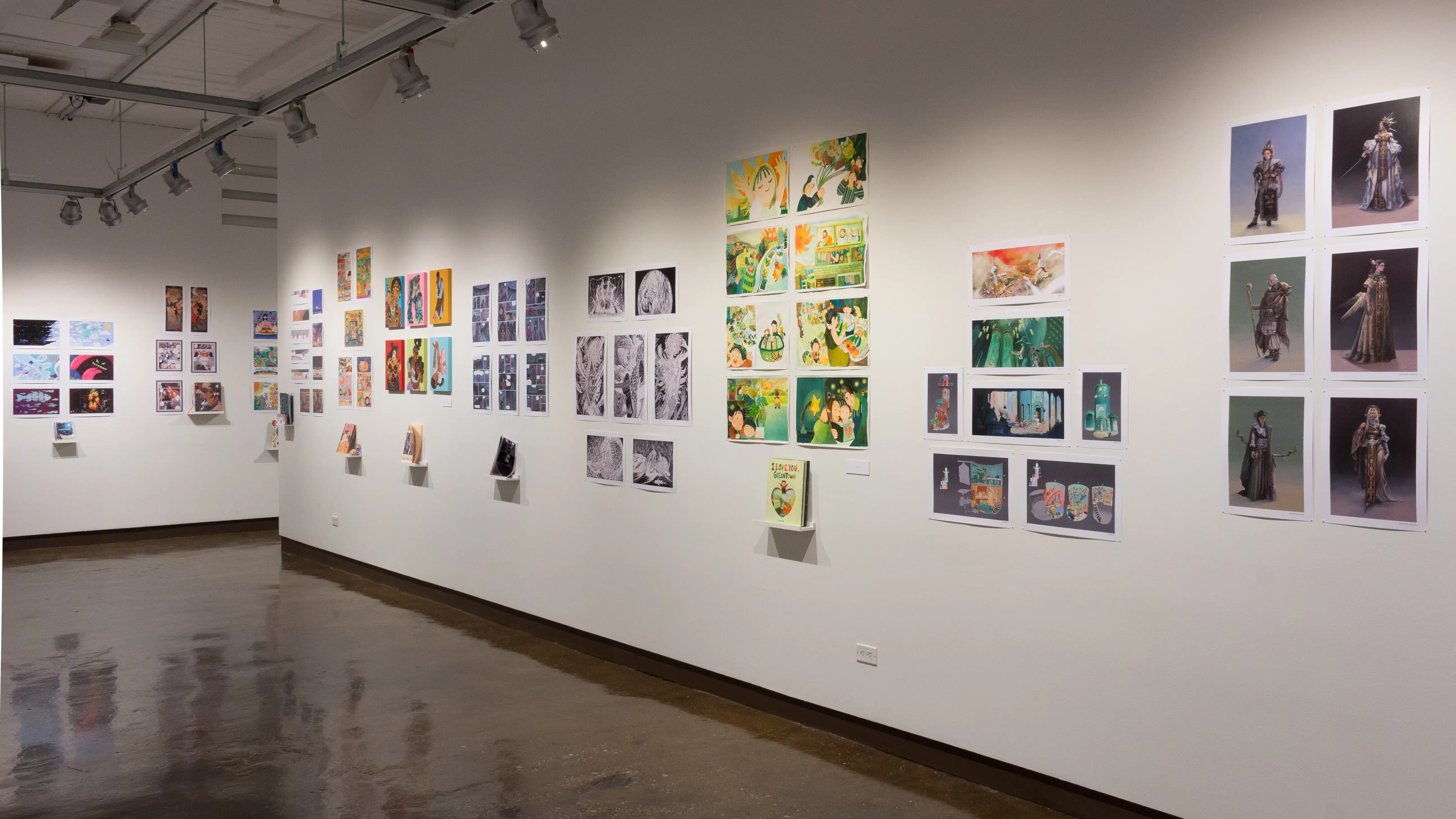 Prints, originals, and books are all displayed on a wall of gallery three.