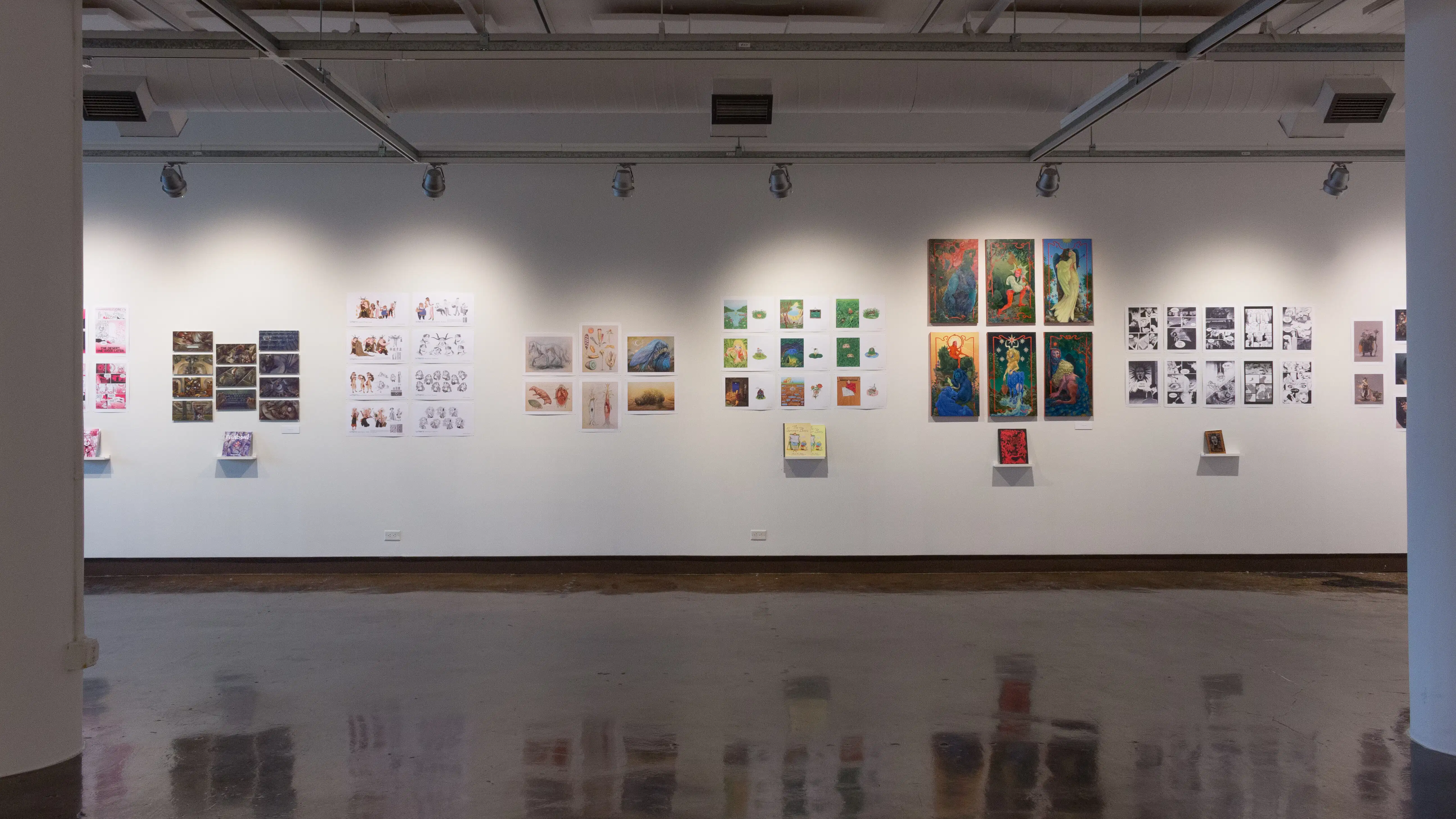 Prints, originals, and books are all displayed on a wall of gallery one.