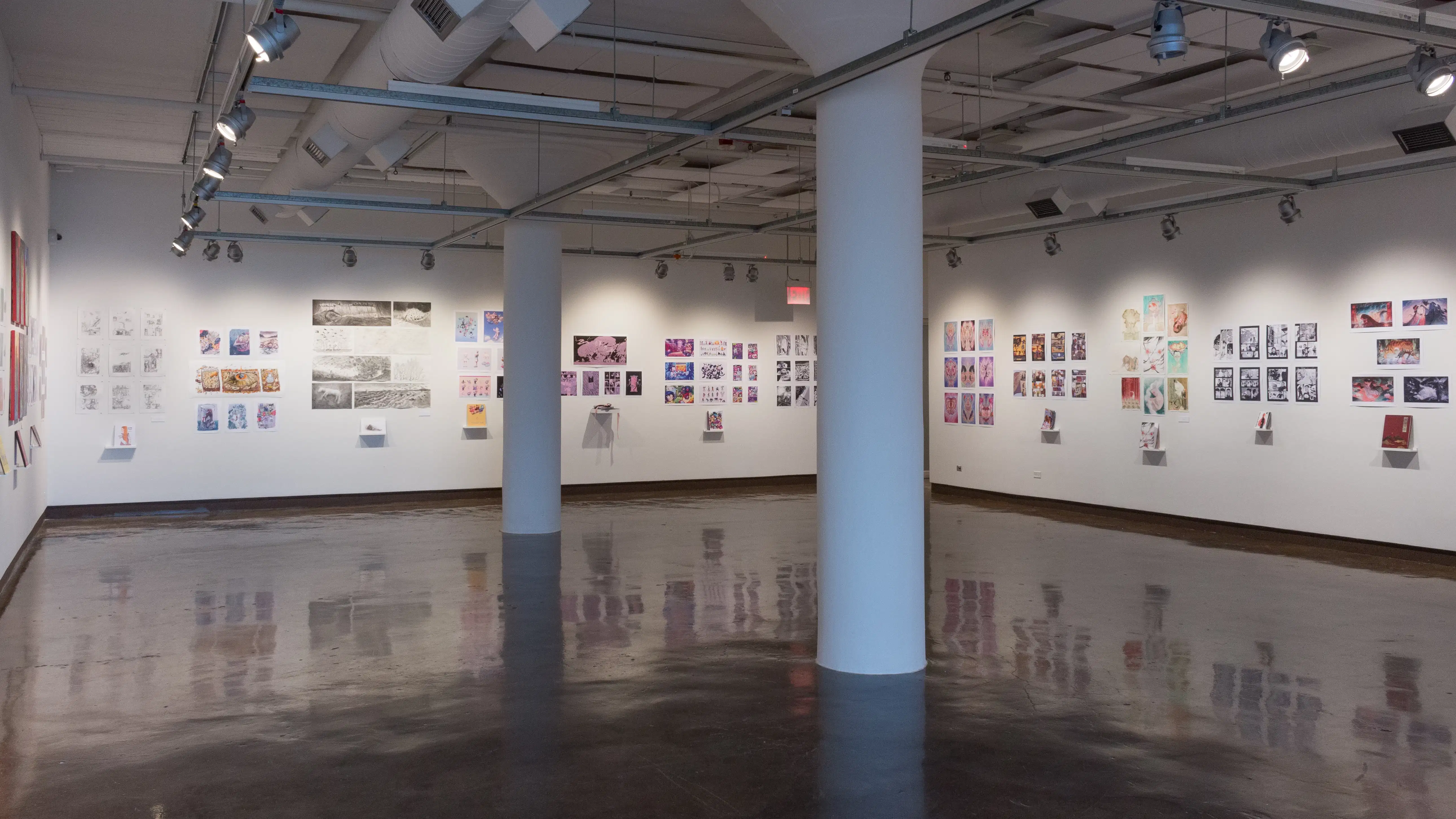 Wide view of gallery one, where prints, originals, and books are displayed on the walls. 