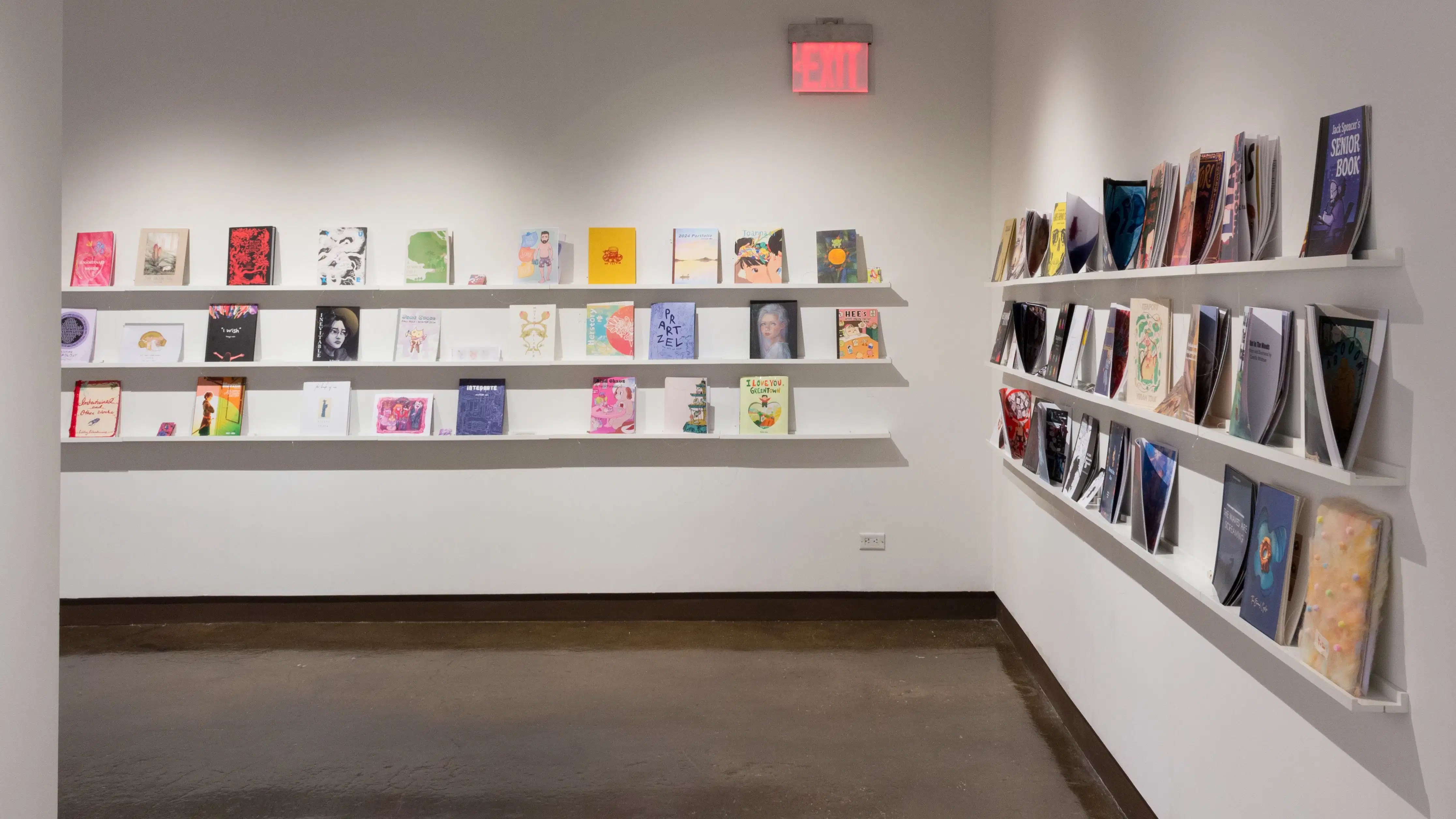 Corner view of gallery four where books are displayed in three rows on shelves across the wall.