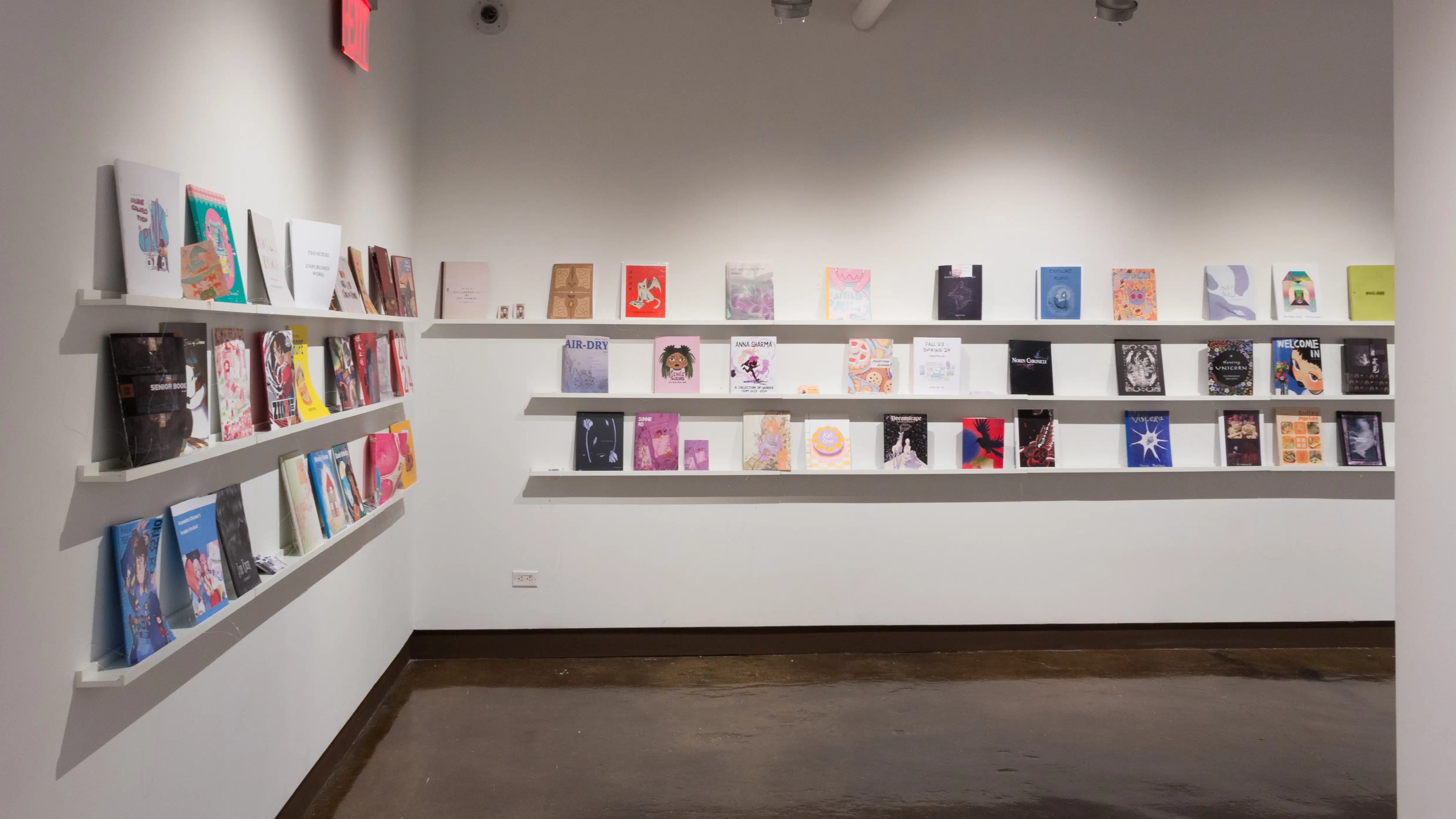 Corner view of colorful books that are displayed in three rows lining the walls of gallery four. 