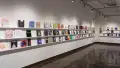 Books are displayed in three rows on long shelves that span the width of gallery four.