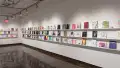 Colorful books are displayed in three rows on long shelves that span the width of gallery four.