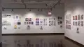 Corner view of prints, originals and books that are displayed along the walls of gallery one. 