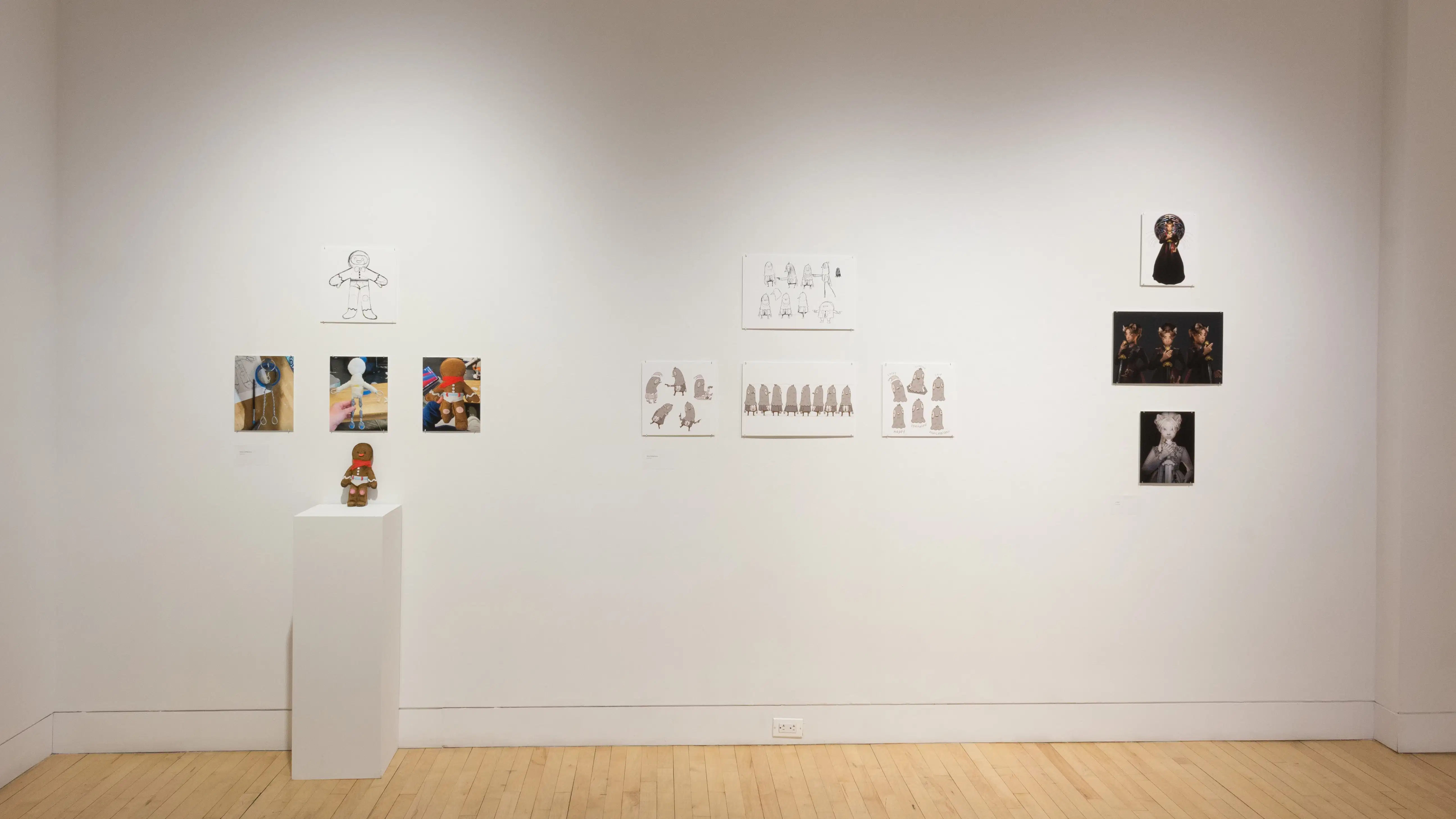 Front view of three student works, showing printed mockups of animated characters and a 3D character display on a pedestal. 