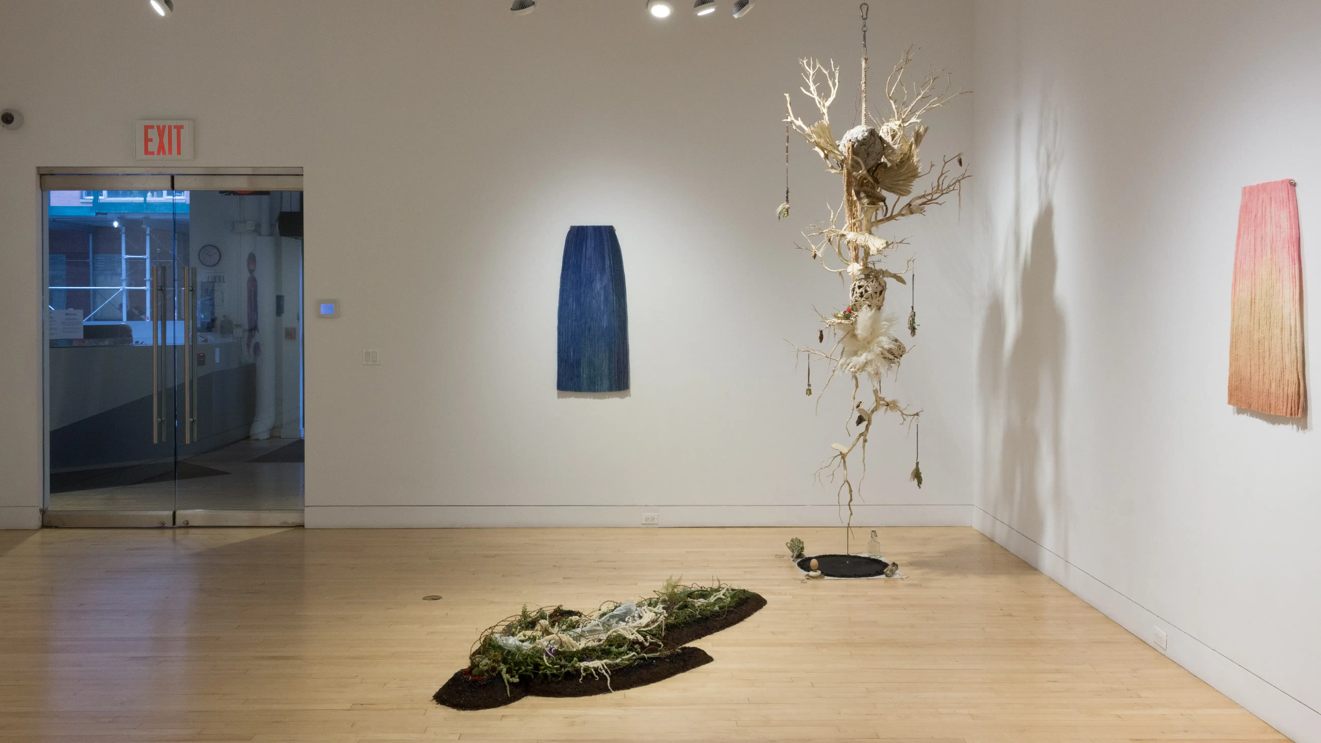 A view of the front wall in the SVA Flatiron Gallery shows a large hanging sculpture, floor installation piece and two wall sculptures. 