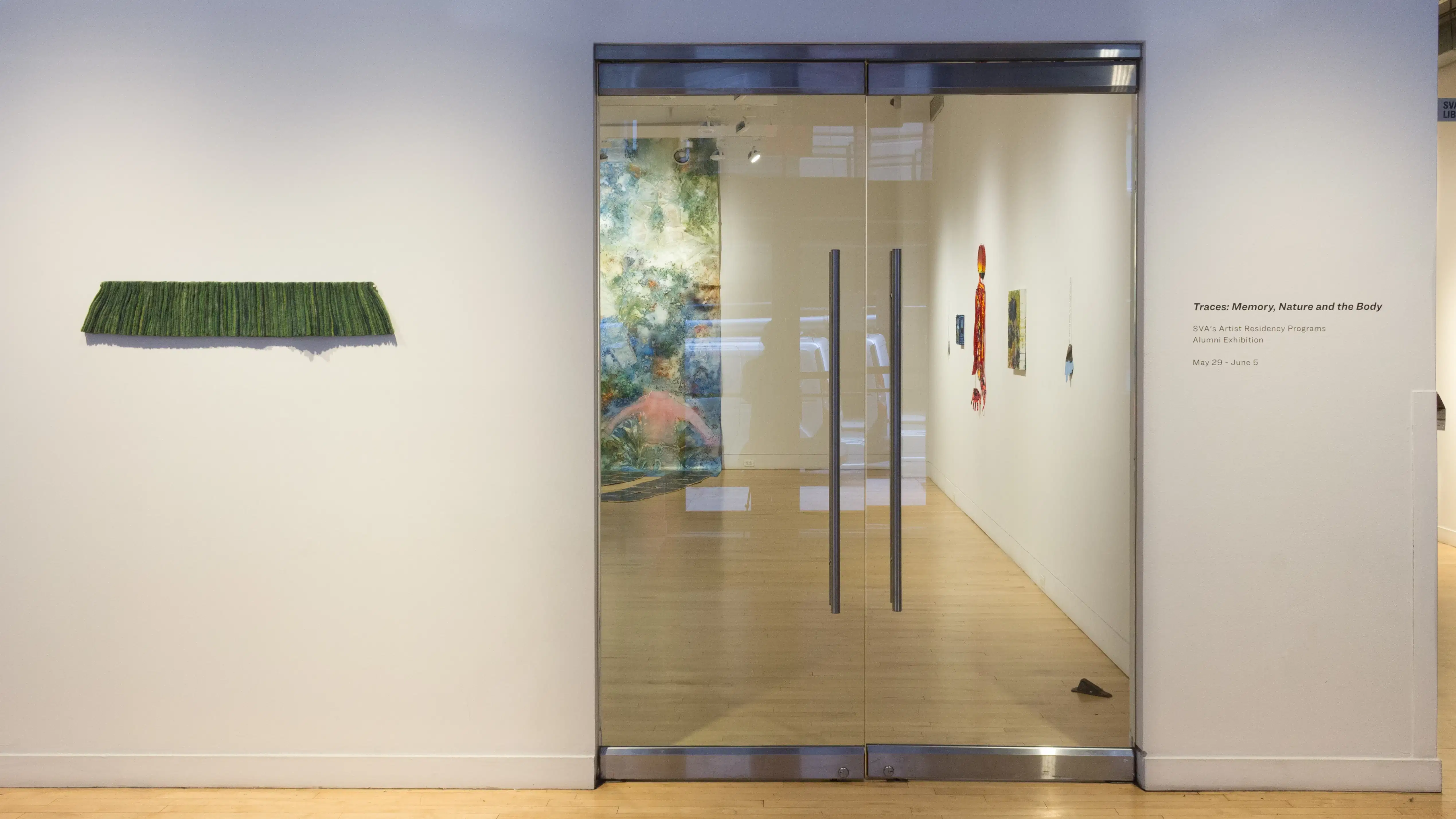 A view of the entrance of the SVA Flatiron Gallery highlights a single sculpture piece and vinyl signage that reads “Traces: Memory, Nature and the Body, SVA’s Artist Residency Programs Alumni Exhibition” 