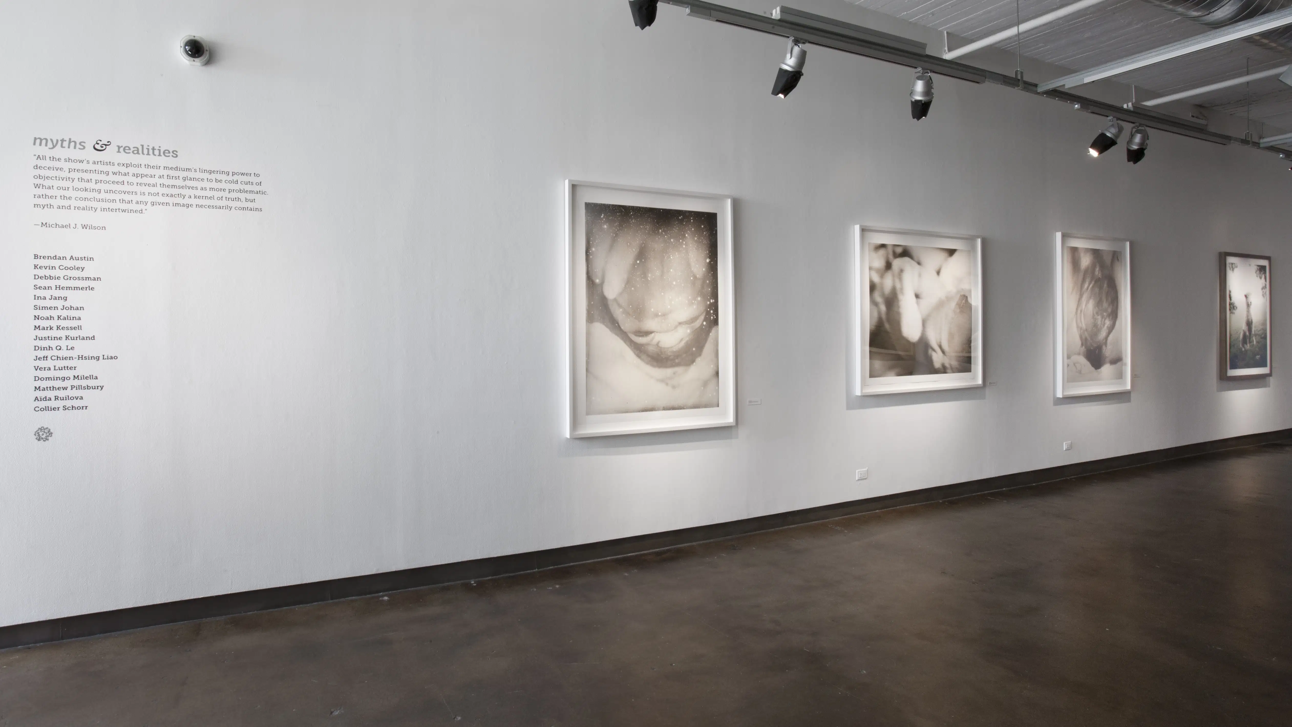 A hallway displaying black and white art. There is a description of the exhibition on the wall.