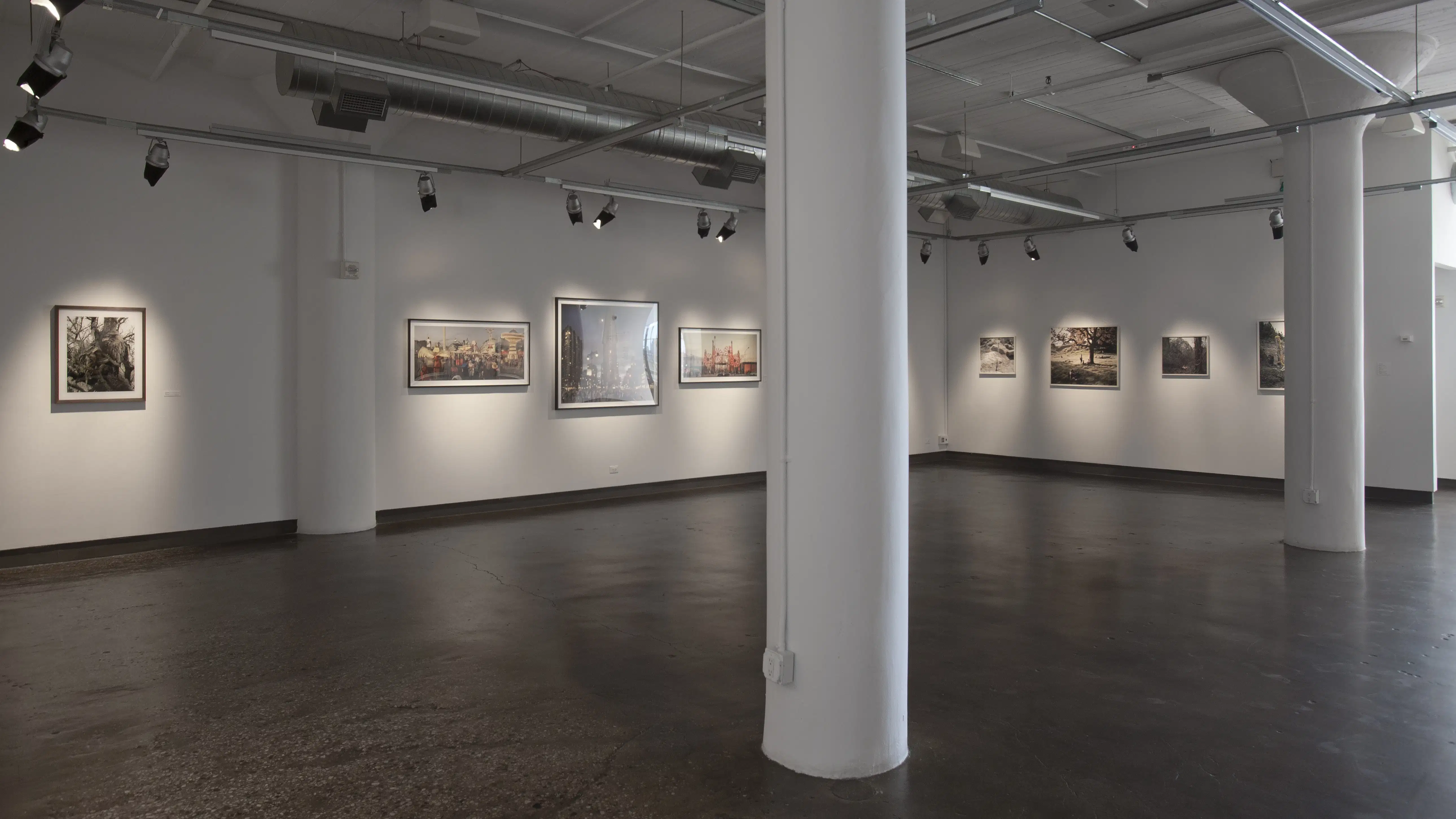 A gallery with framed photographs on the wall, white columns are in the foreground.