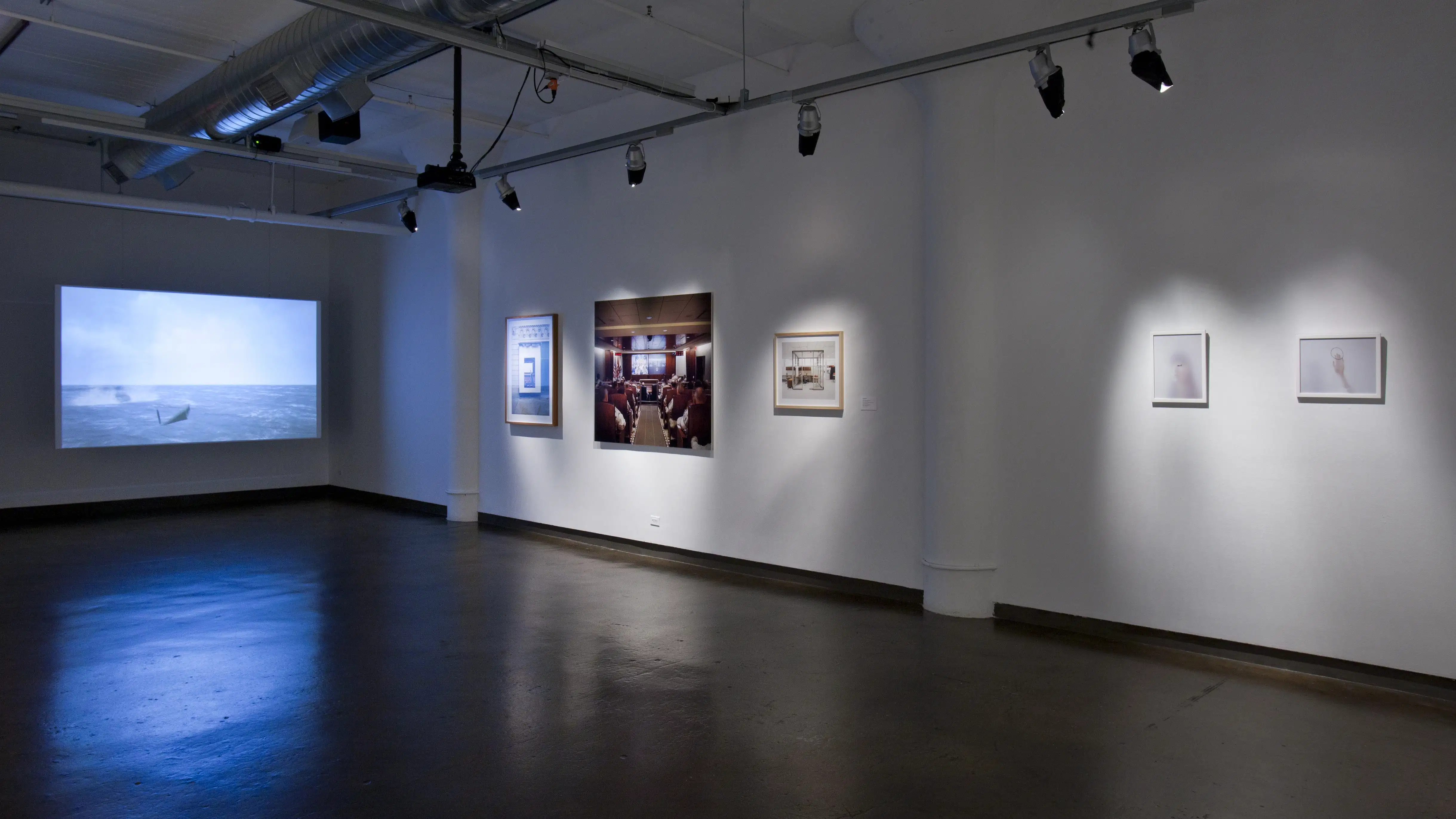 An art gallery with a motion picture being projected on the wall.