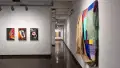 Installation image showing 3 color photographs on the left, a hallway down the middle and a large fabric installation on the right.