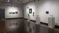 Installation image showing 3 color photographs on the far back wall, three pedestals with ceramics and unframed photo installations behind.