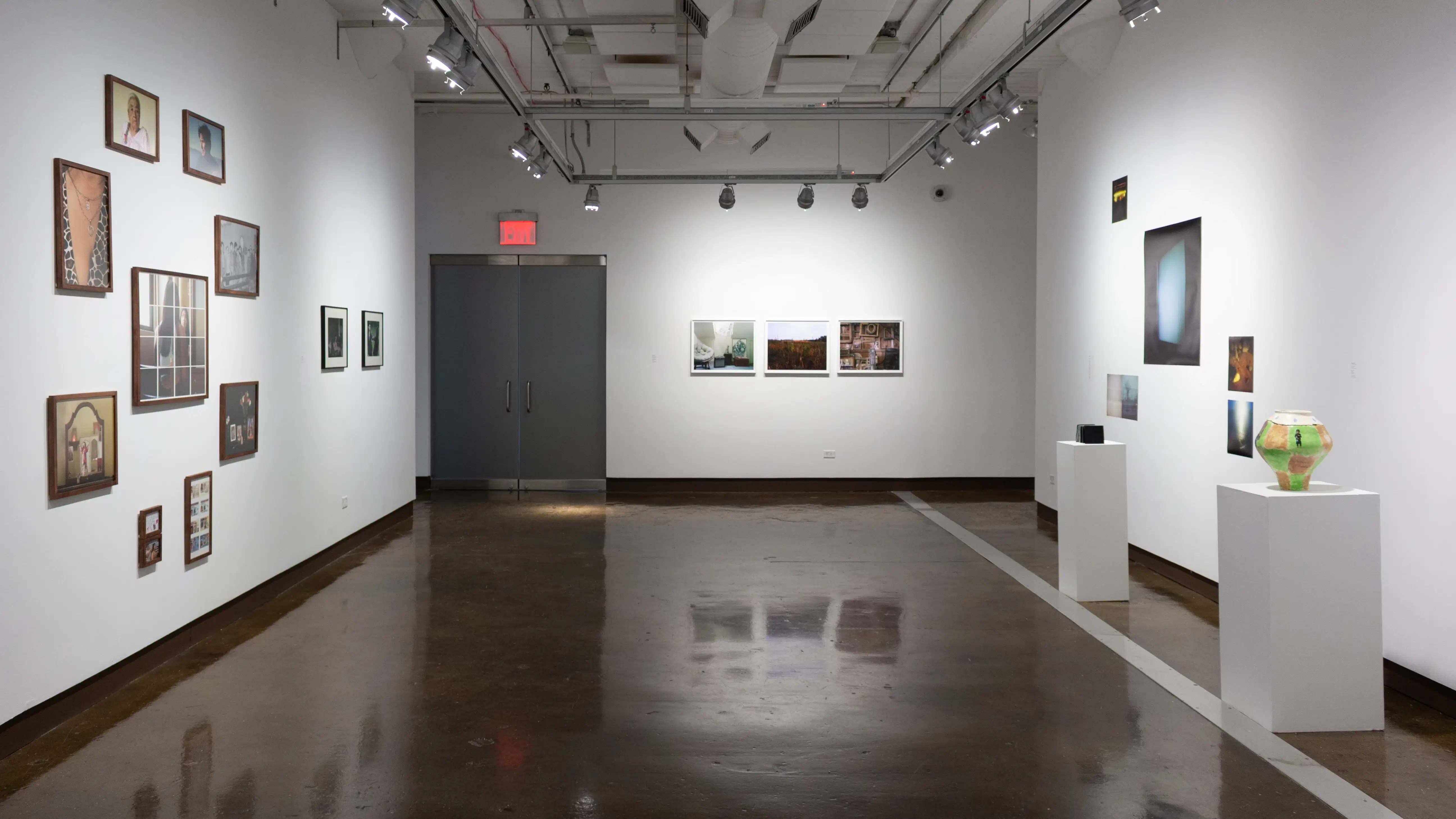 Installation image showing 11 framed photos on the left wall, three framed photos on the back wall, two pedestals with ceramics and photo installations behind on the right.