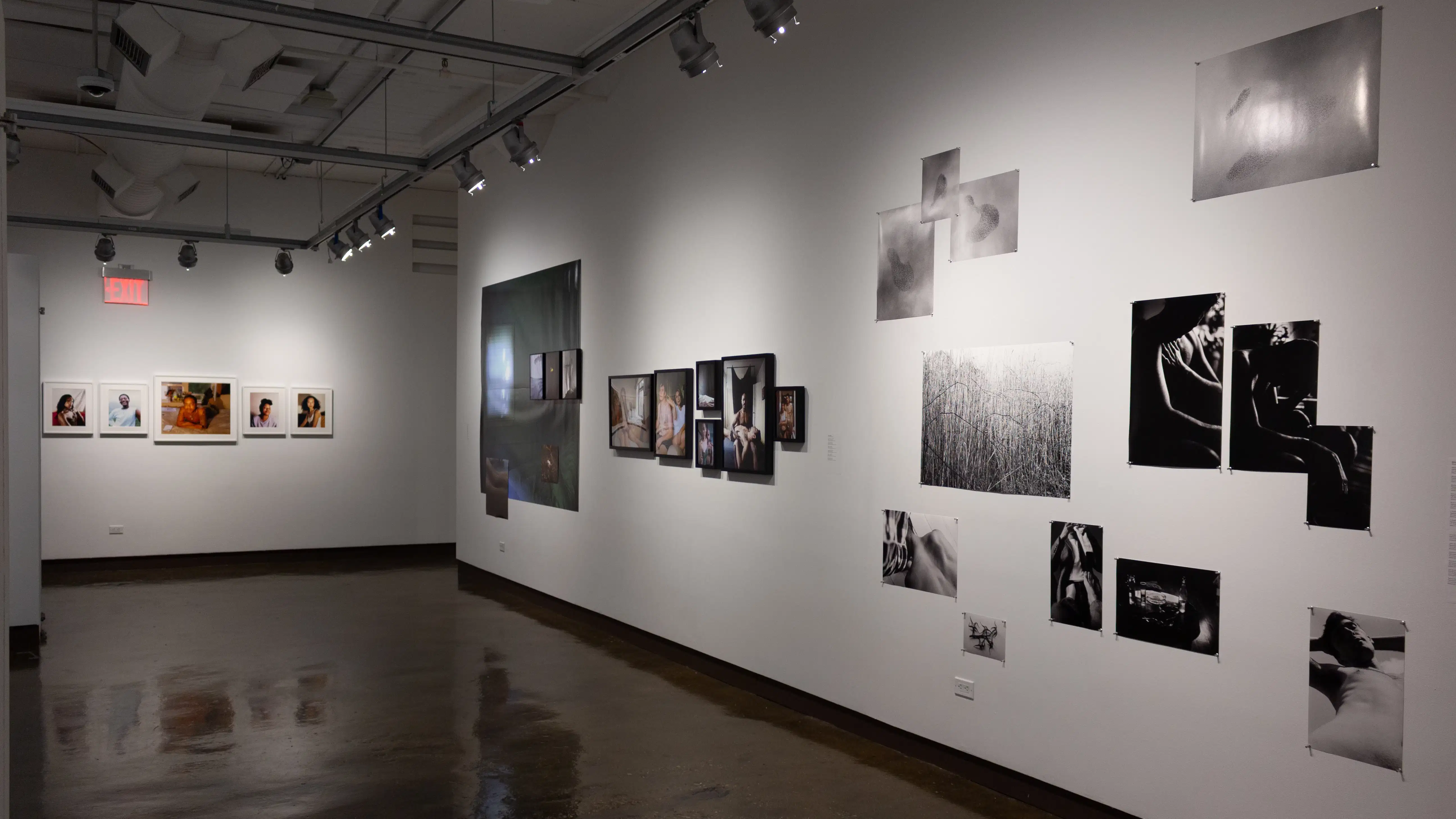 Installation image showing installations of black and white and color photographs on a long wall on the right, and 5 framed color photos on a far back wall.