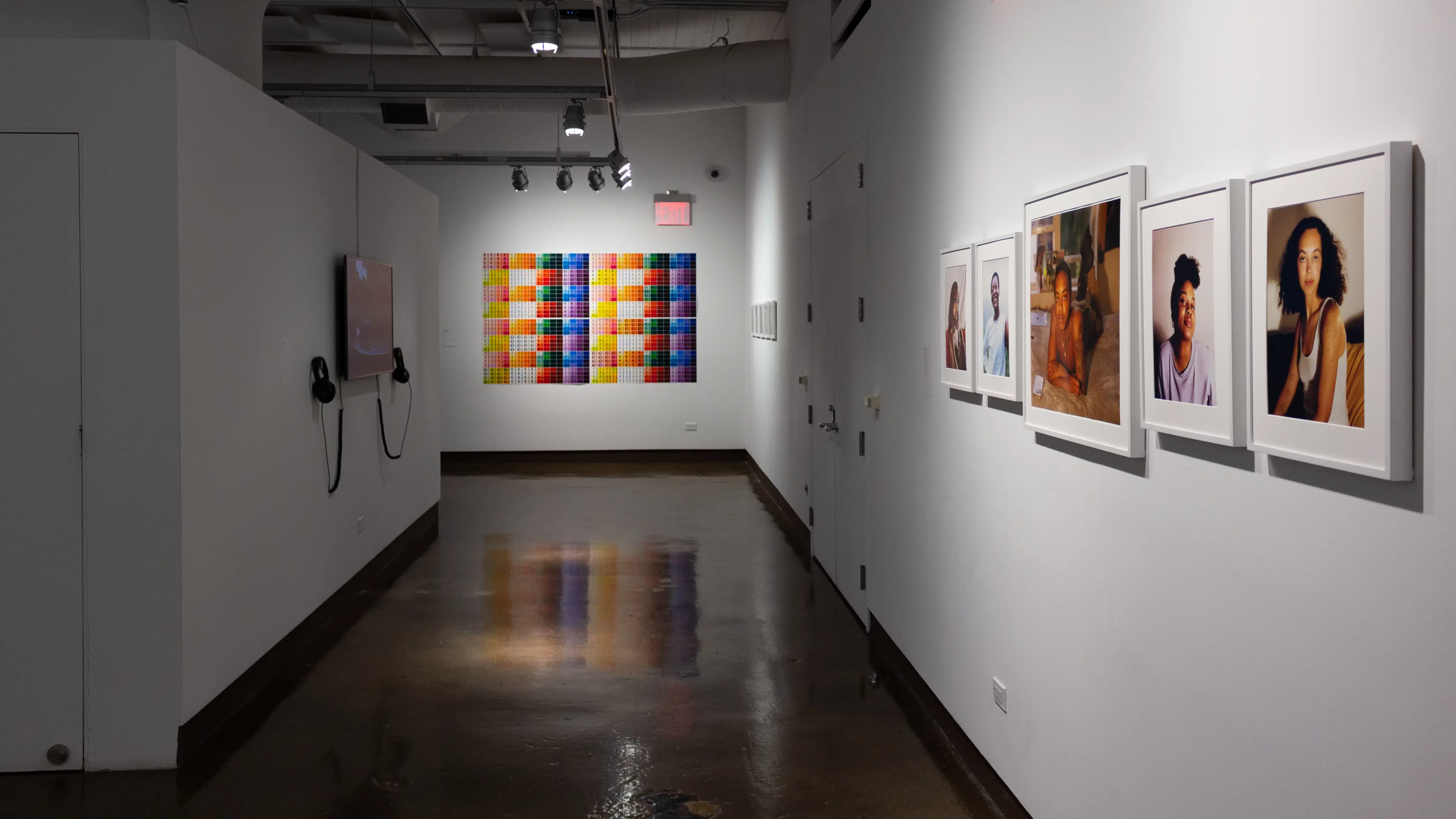 Installation image of a hallway with a monitor on the left, a large color grid on the wall in the back and 5 color photographs on the right wall.