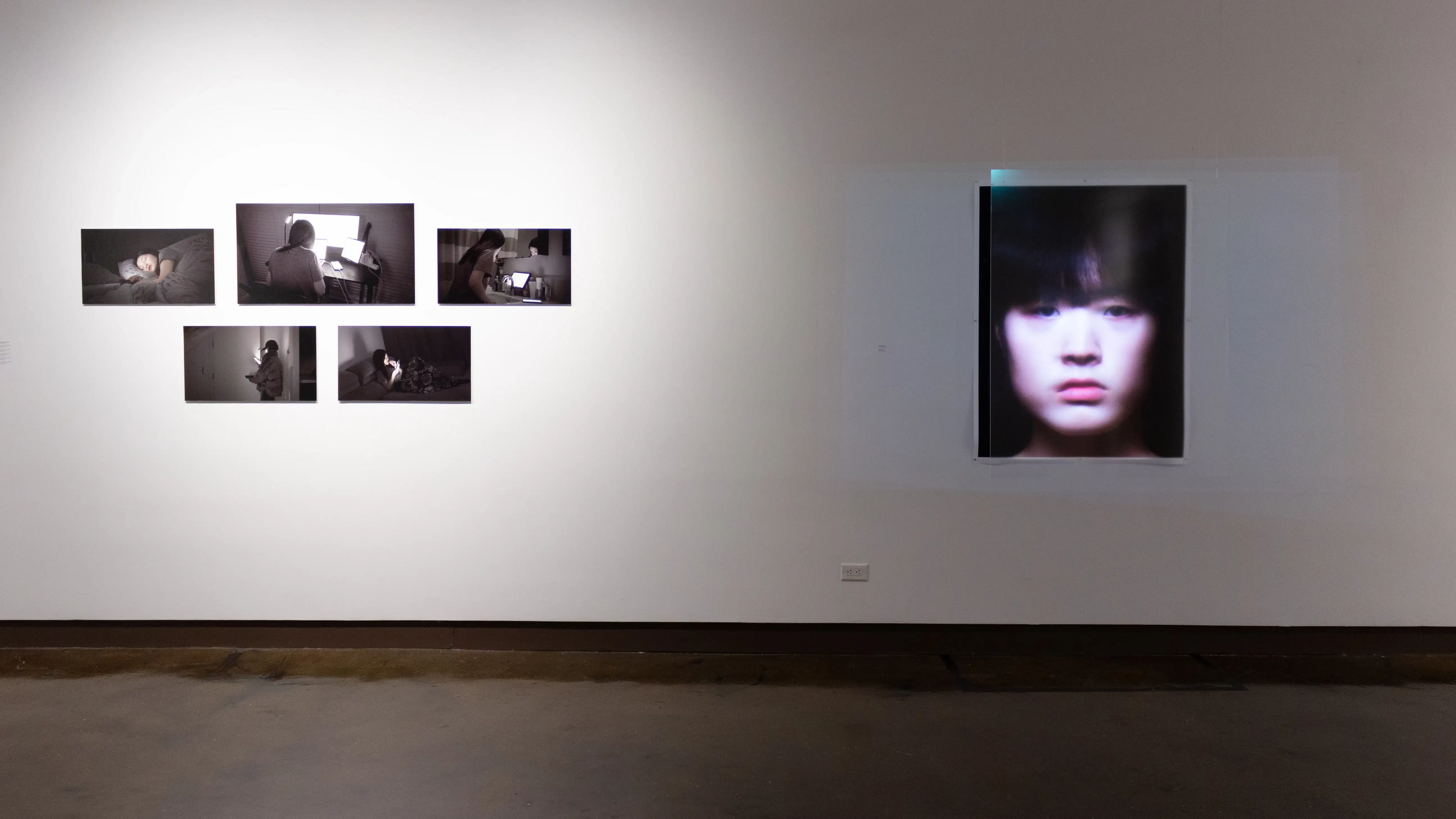 Installation image showing 5 black and white photos on the left and a large portrait on the right.