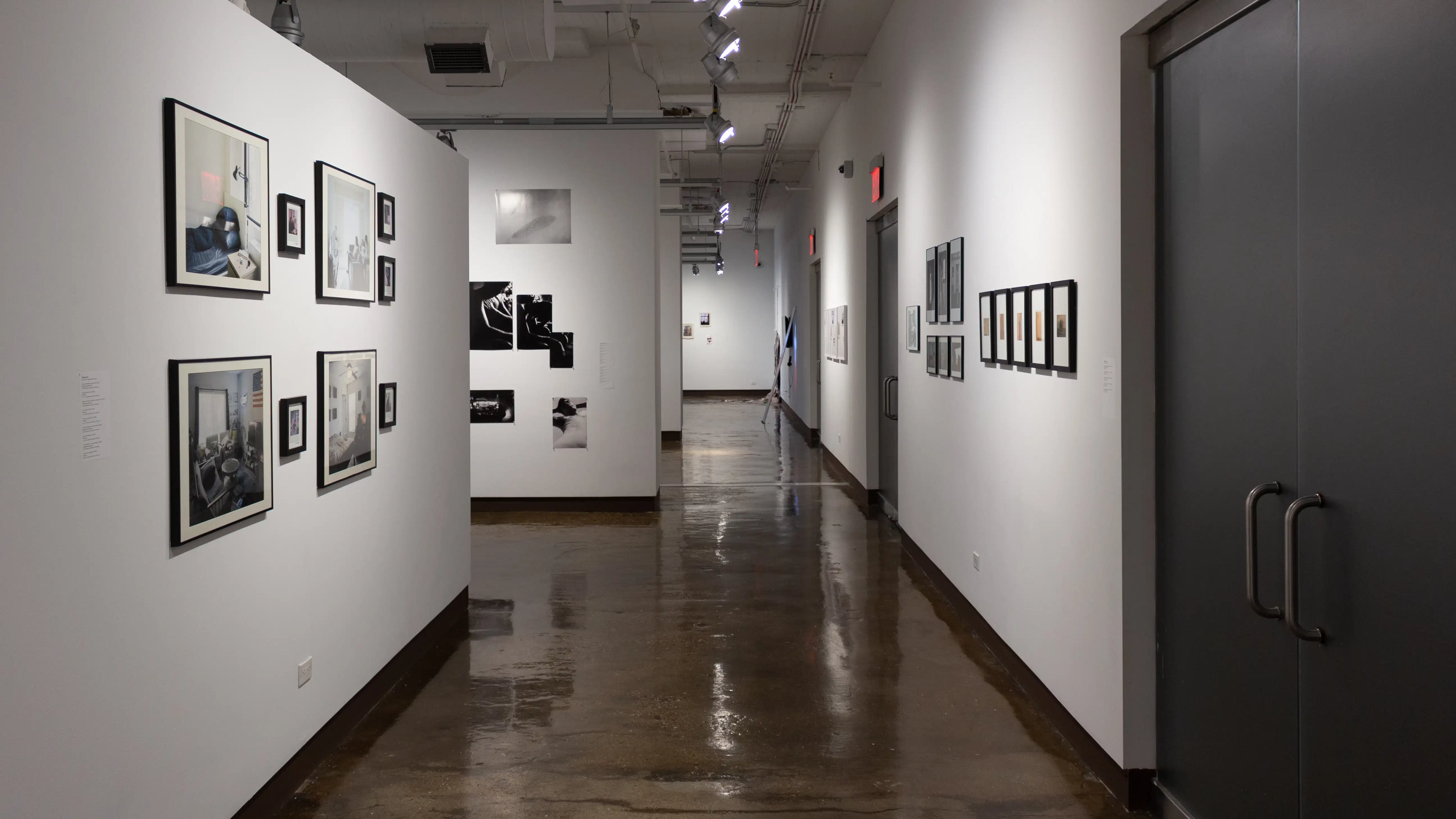 Installation image showing 12 framed photos on the left wall a long hallway to the front gallery.