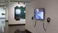Installation image featuring video work on monitor in the foreground and a photo installation in the background with a hallway to the left.